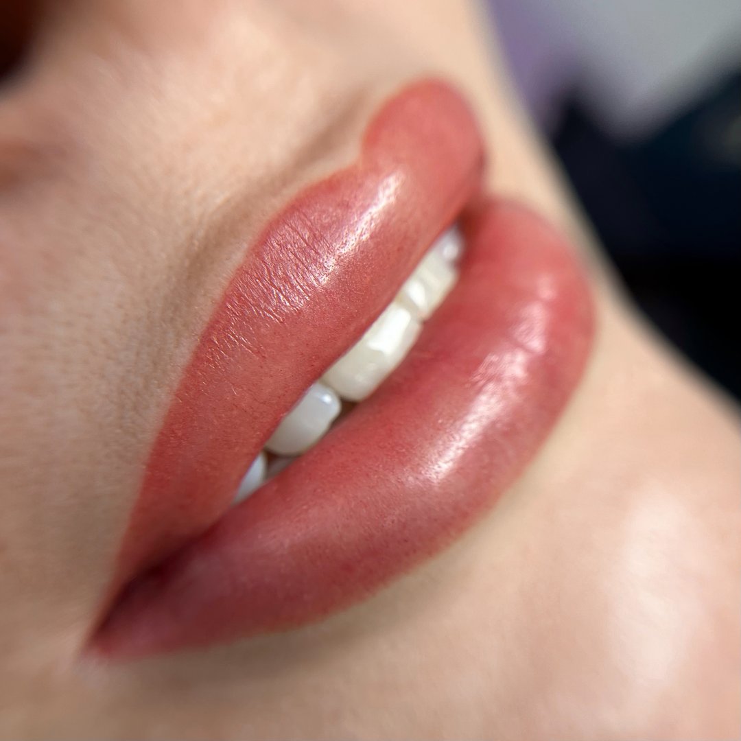 permanent makeup on the lips of a young woman of a delicate peach shade close-up