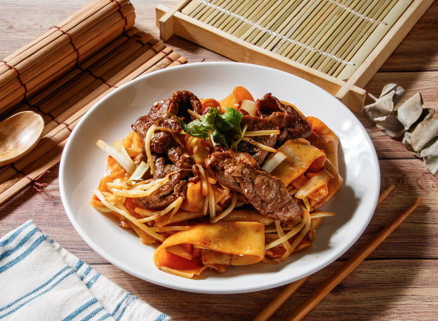 Hong Kong Style Fried Beef Noodles served in plate with chopsticks and spoon isolated on wooden table side view of taiwan food