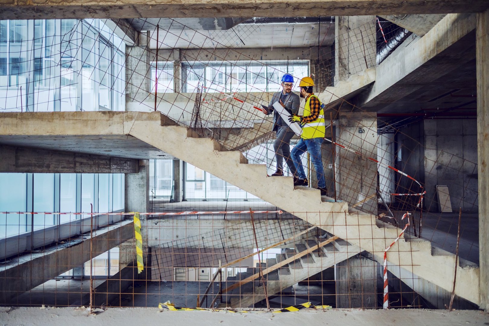 Construction worker and main architect climbing the stairs and talking about progress