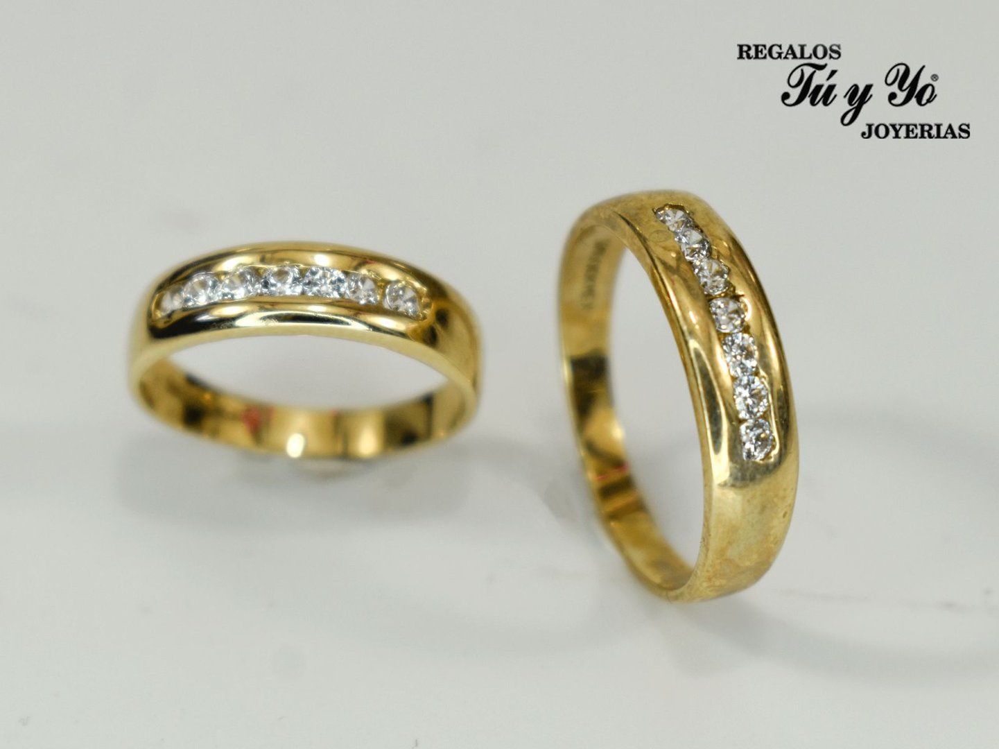 Two gold rings with inline diamonds on a white background, featuring jewelry shop branding in the upper right corner.