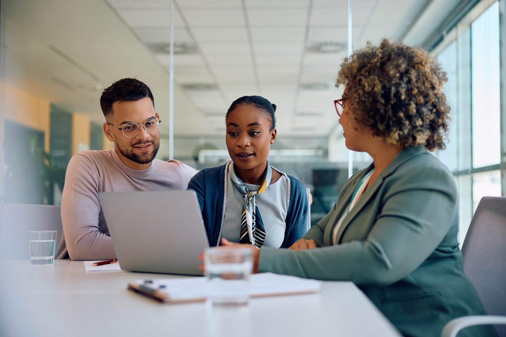 Young multiracial couple and their insurance agent using computer while having a meeting in the office.