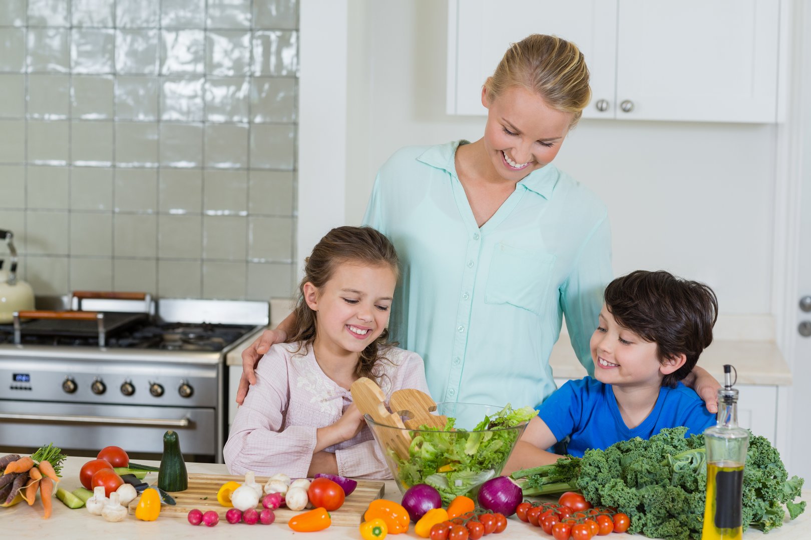 Mother and kids preparing a salad in kitchen at home