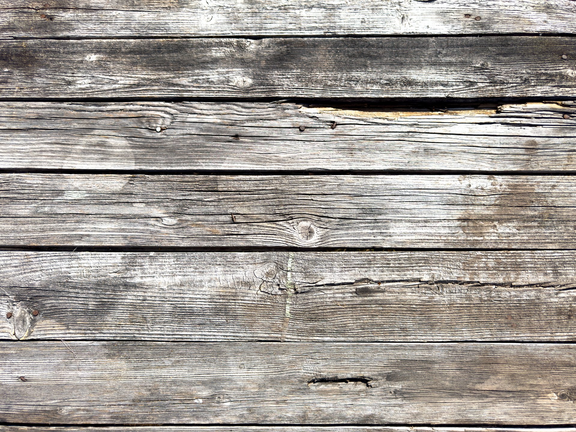 A wooden surface with a grainy texture. The wood is old and worn, with some areas showing signs of decay. Scene is one of nostalgia and a sense of history