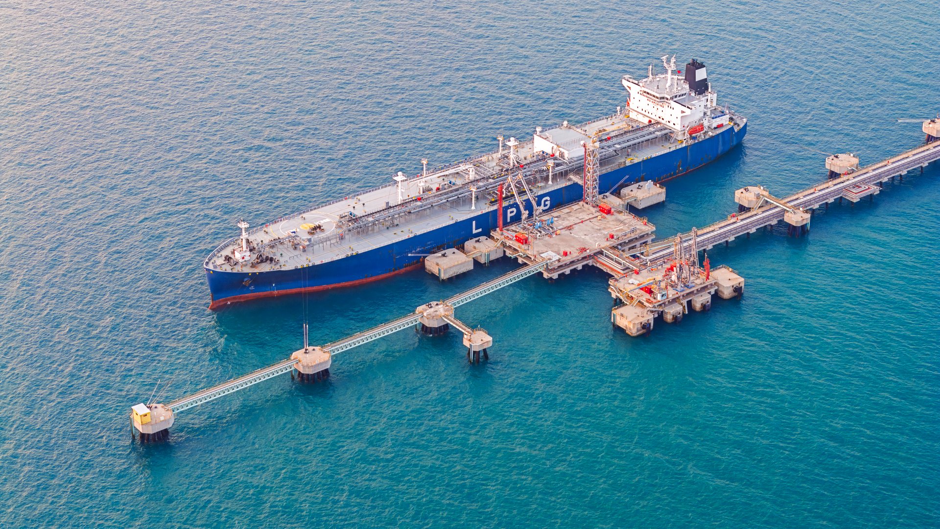 Aerial view oil tanker ship park at loading dock for load or unload oil from refinery.
