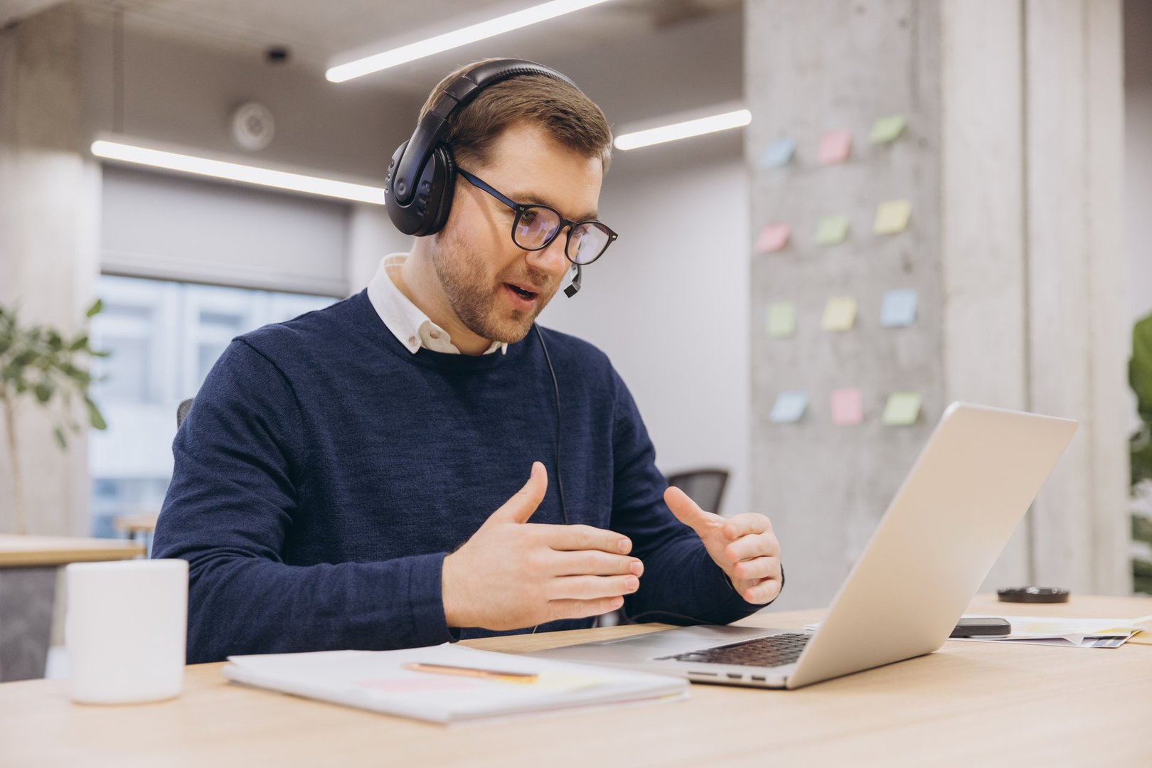 Professional businessman working remotely, speaking animatedly during video conference with headset and laptop