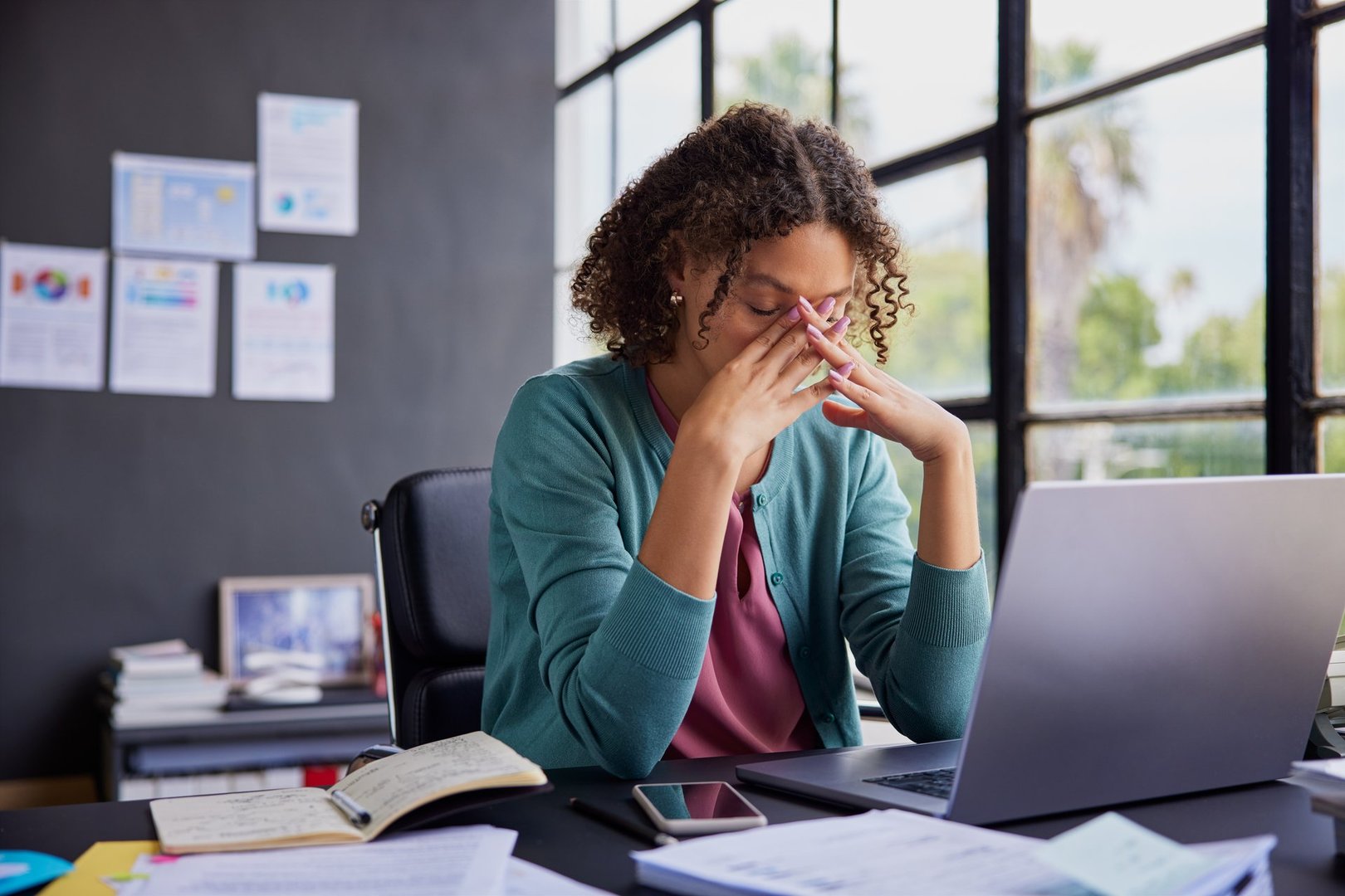 Exhausted businesswoman feeling stressed, holding her head while working on a laptop