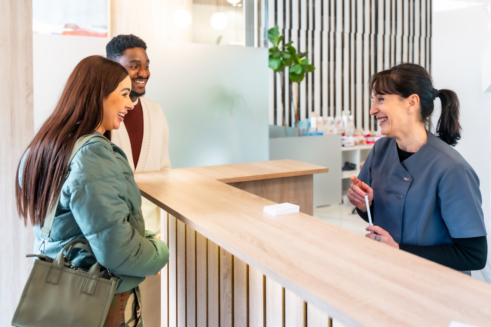 Happy couple communicating with the receptionist at the front desk of a modern dental clinic
