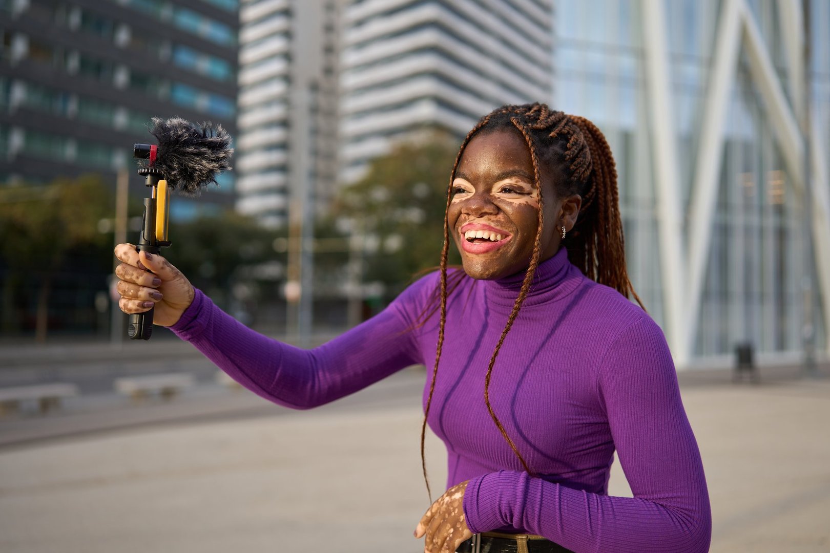 Energetic young woman creating a vlog on her phone in an urban environment