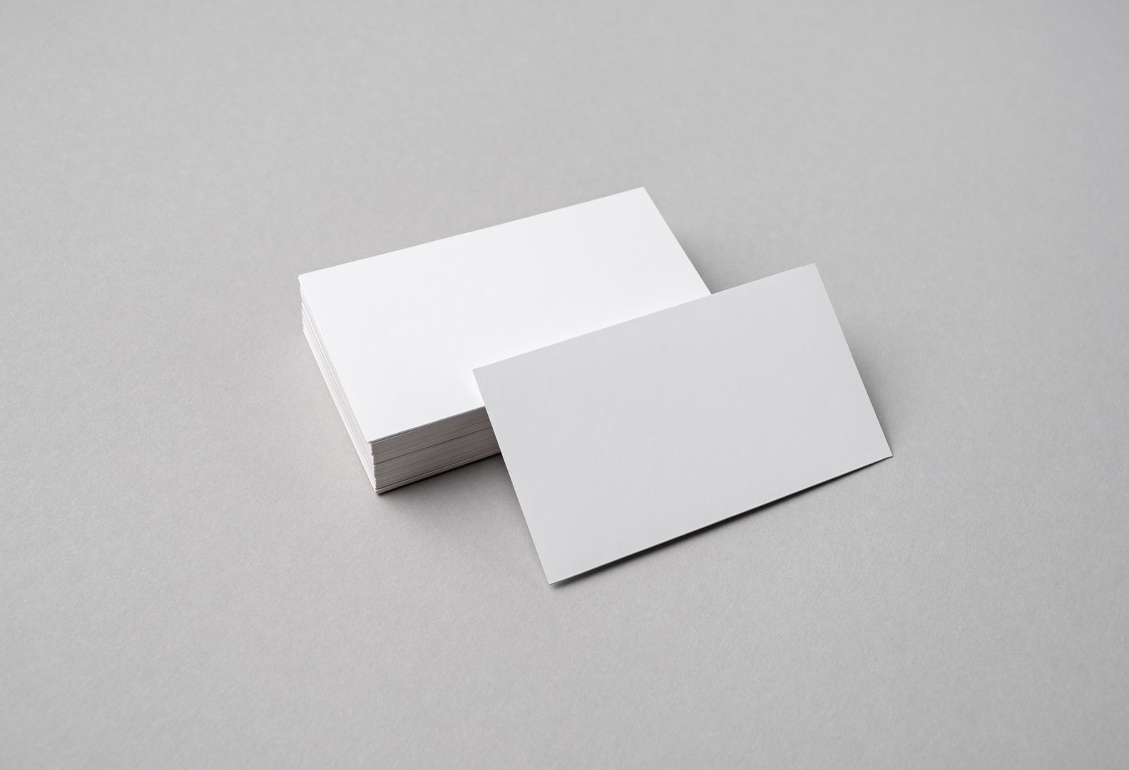 Blank white business cards on gray paper background. Mock-up for branding identity