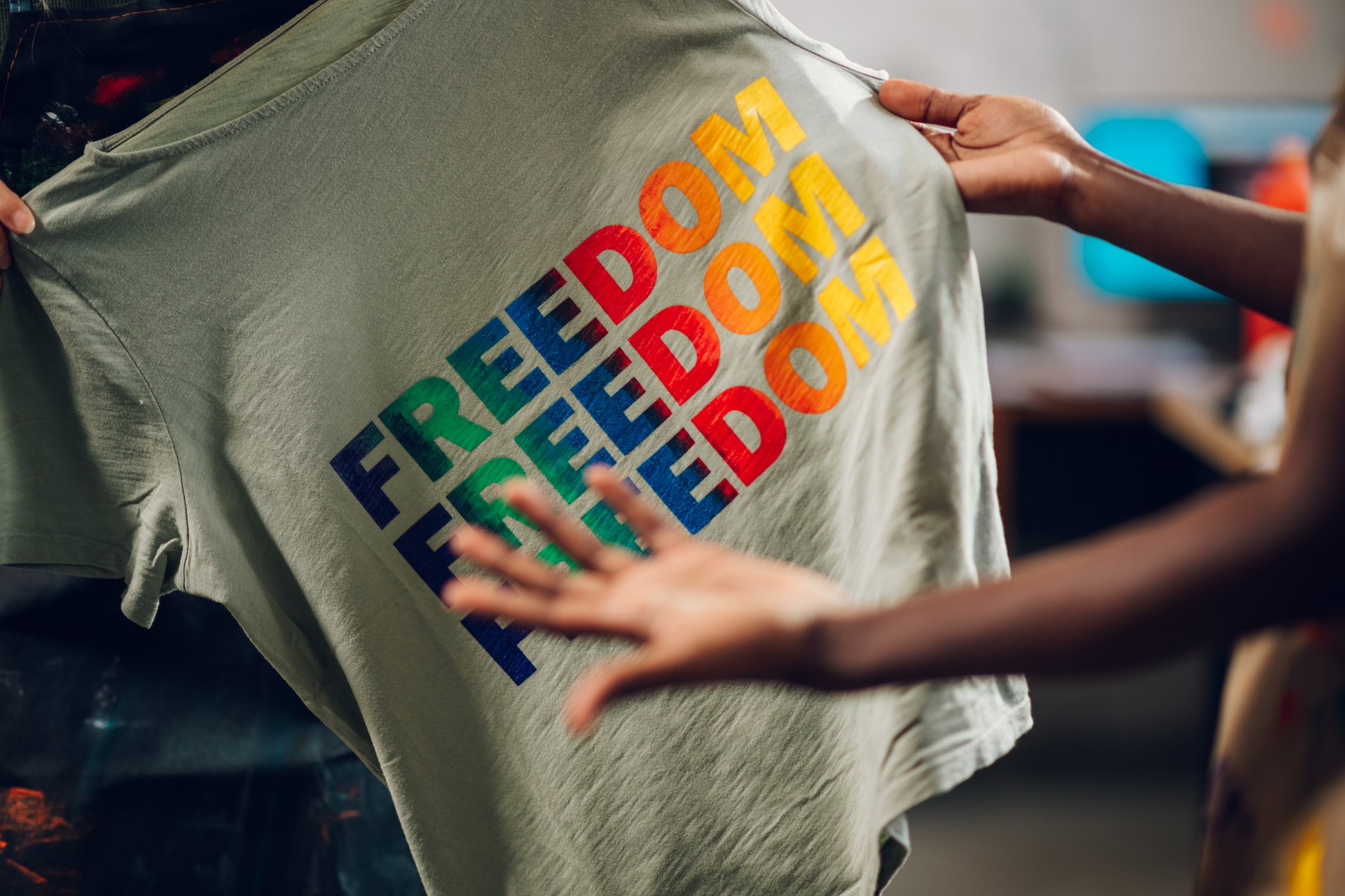 Close up of multicultural female graphic technology experts' hands holding silk screen printed t-shirt at facility. Interracial supervisor doing quality control of printed textile product at facility.