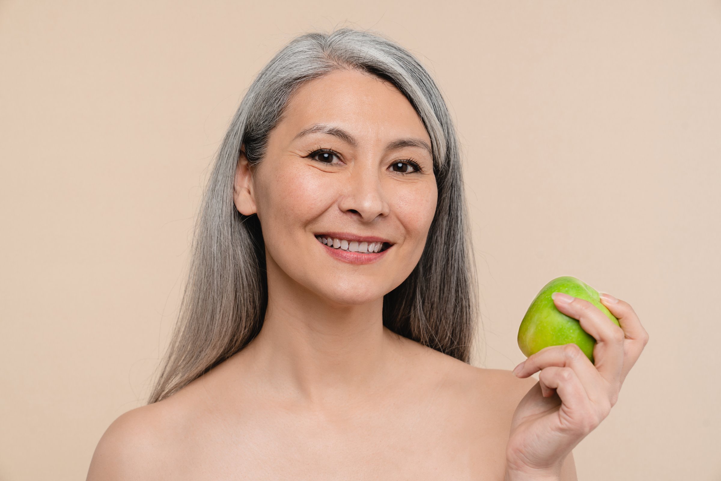 Dentistry stomatology concept. Healthy eating habits. Closeup dietitian nutritionist mature middle-aged woman showing green apple for balanced diet for weight loss. Skin and hair care