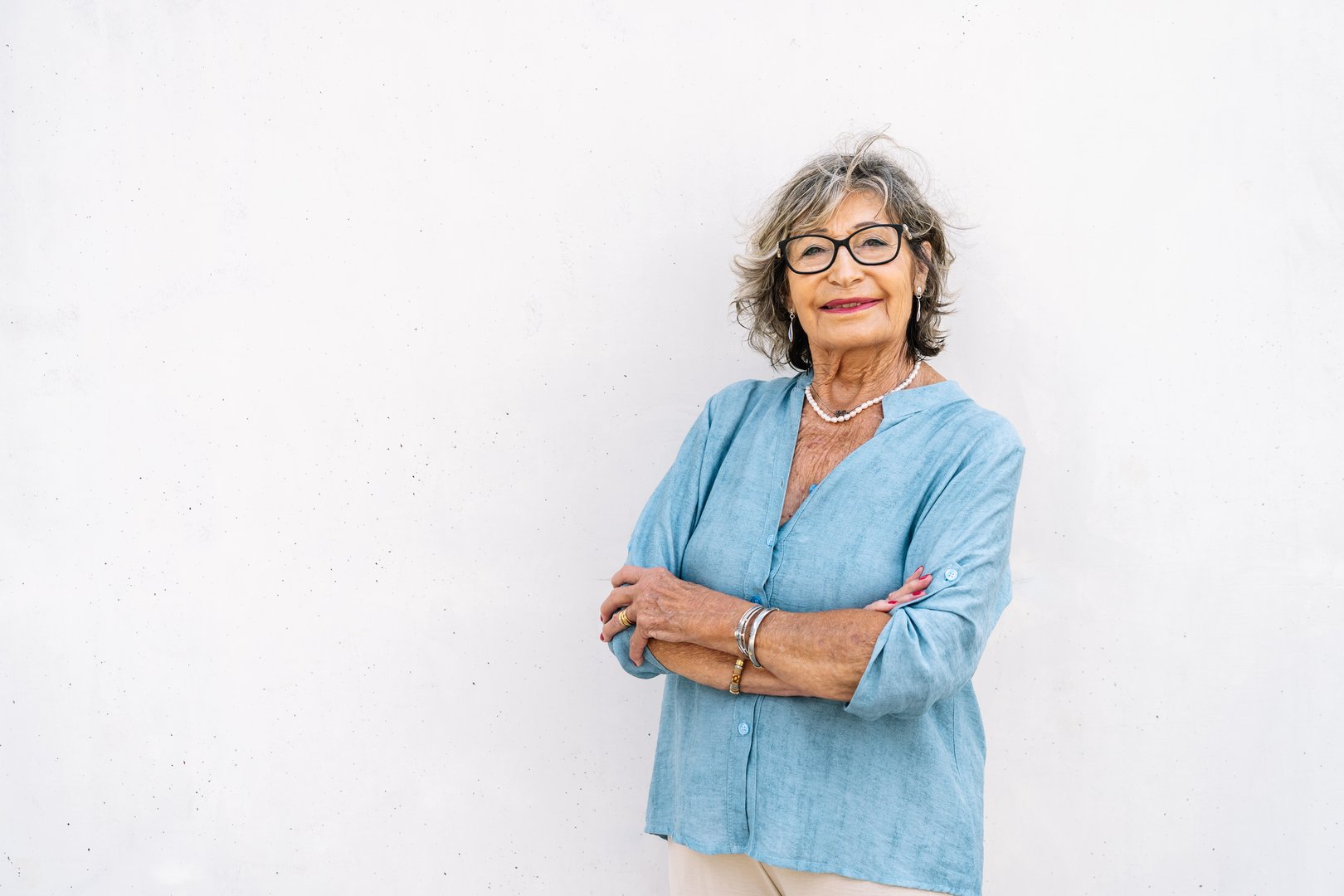 Confident mature adult woman looking at camera with a happy expression against a plain wall