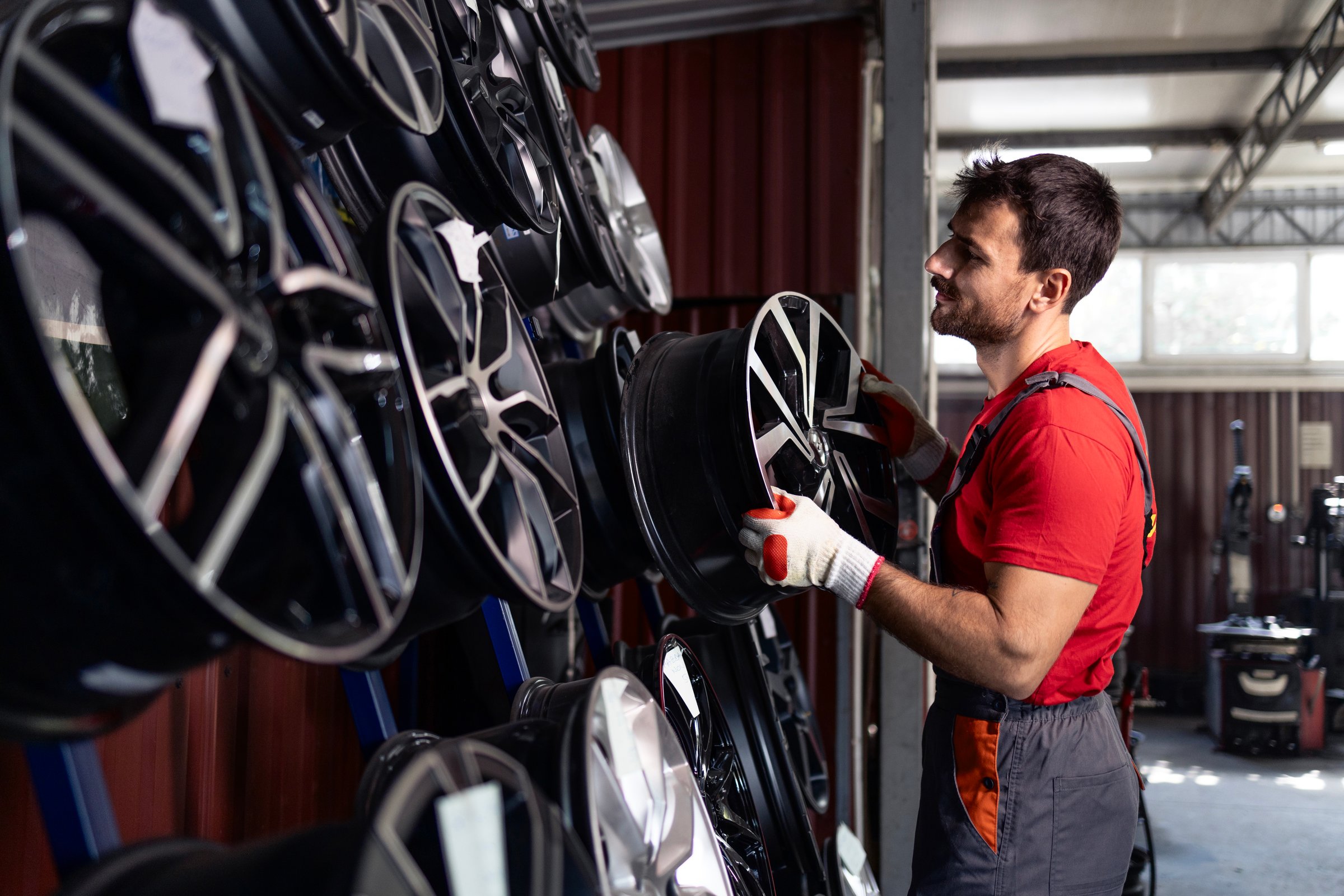 Tire shop worker arranging car rims for sale.