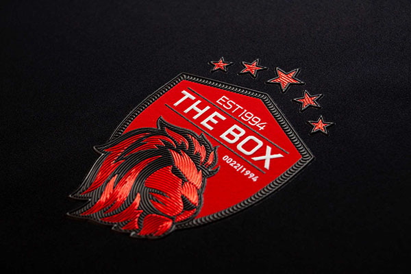 Red logo with a lions head, titled The Box and five stars above, includes EST 1994 and 002211994 on a black background.