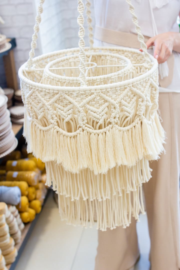 Woman shows macrame lampshade in craft store, home decor show room, handmade concept market, hobby goods bazaar