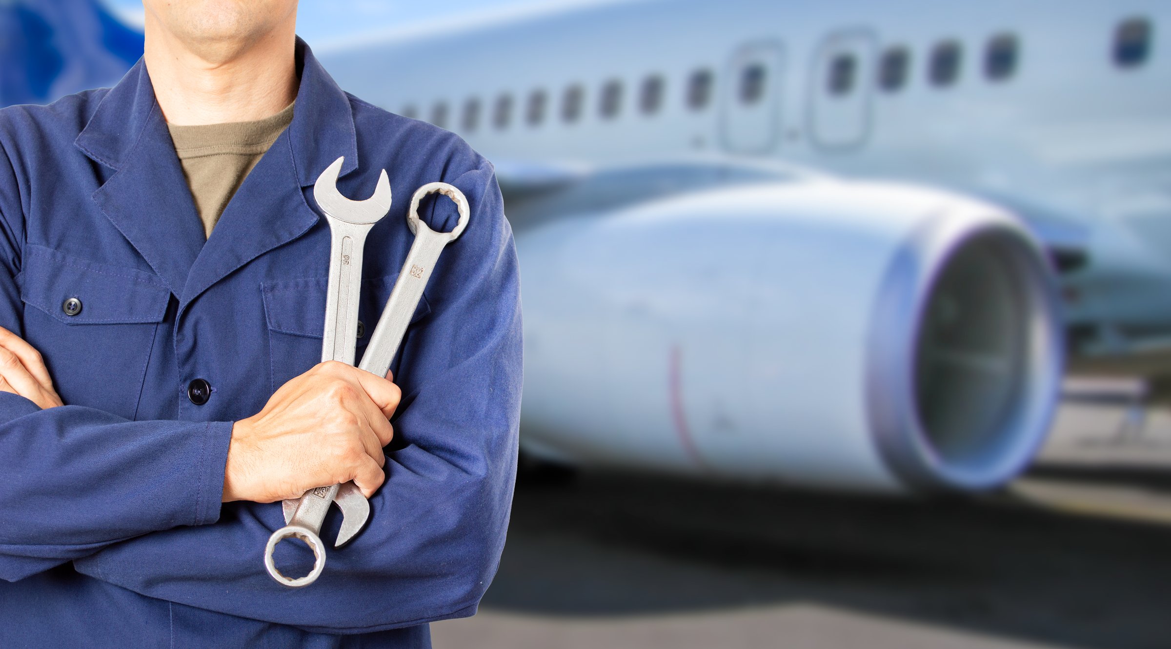 Aircraft mechanic, with tools or spanner for handyman, maintenance or repair work with jet engine in the hangar at the airport.