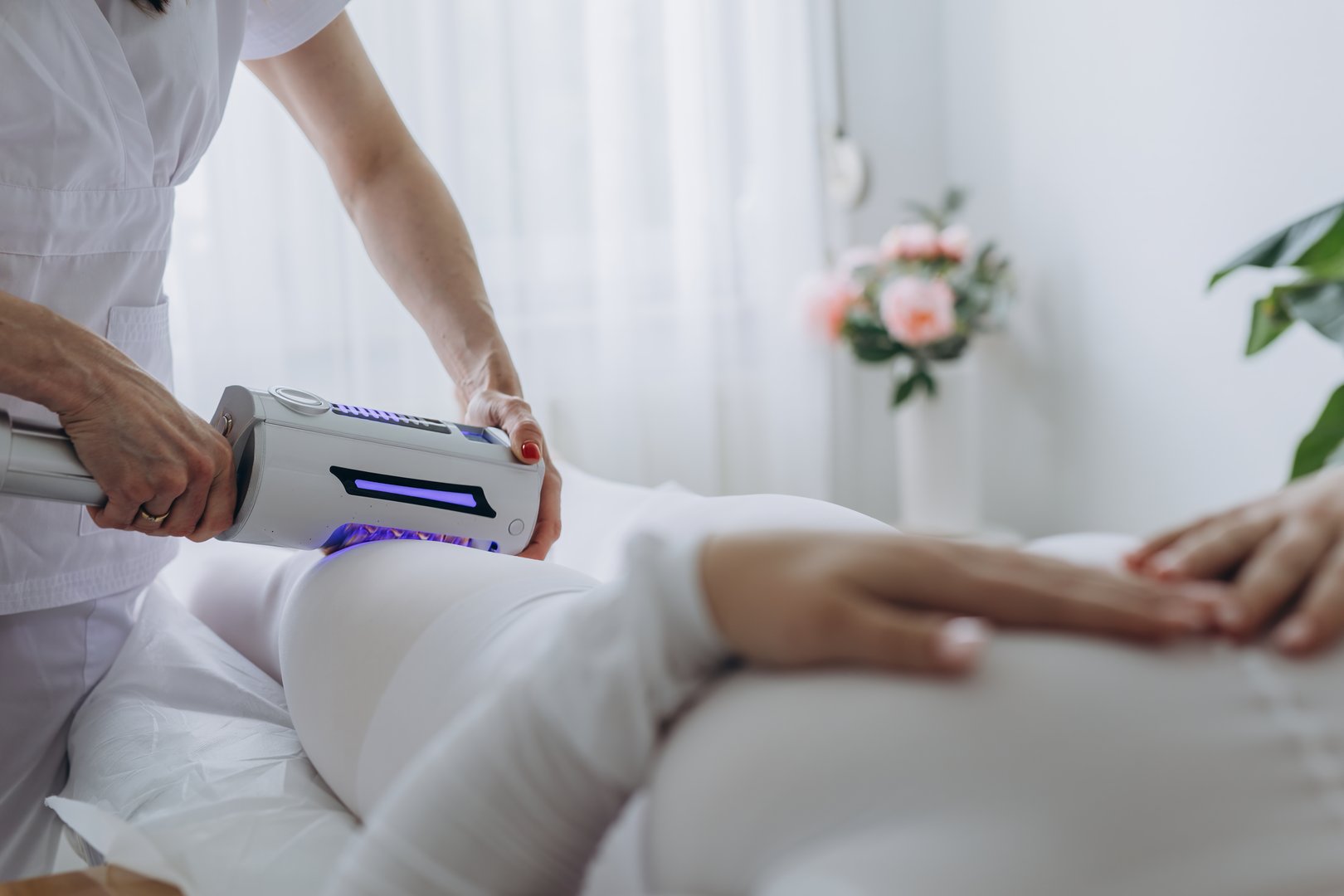 Anti-cellulite Microvibration Therapy session in a beauty clinic. A woman in a white bodysuit receives hardware body massage treatment for slimming, shaping, and lymphatic drainage. High quality photo