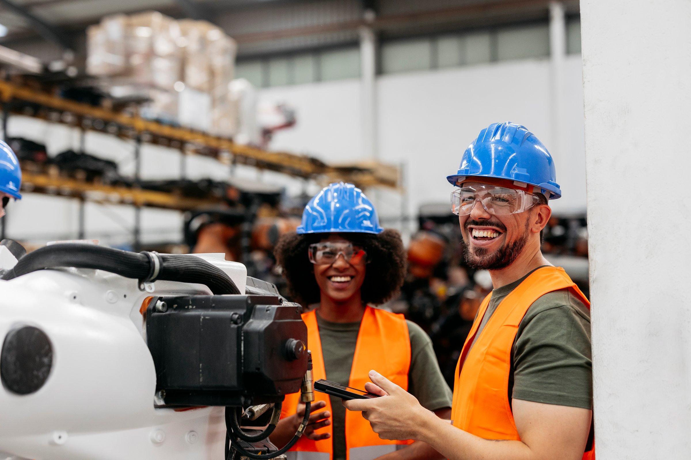 Multiracial engineers program a robotic arm with a smartphone in a high tech factory, showing innovation and teamwork in modern manufacturing