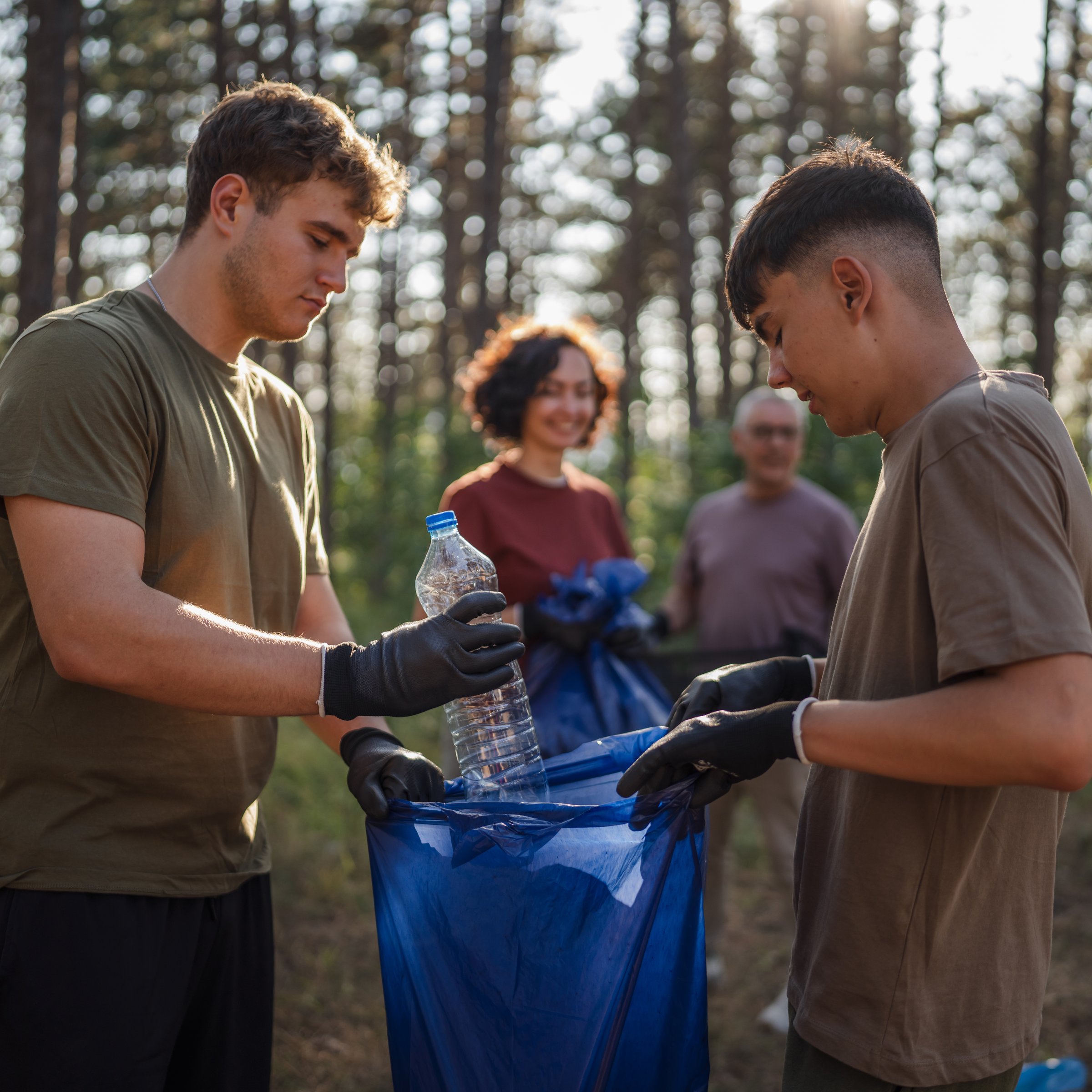 family of volunteers men woman pick up waste garbage to clean forest