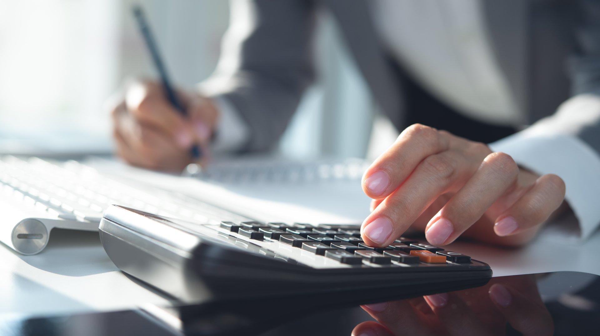 Close up, business woman working at office, using calculator to calculate company finance, accounting with laptop computer on table, budget management. Doing finance, budgeting and tax calculation