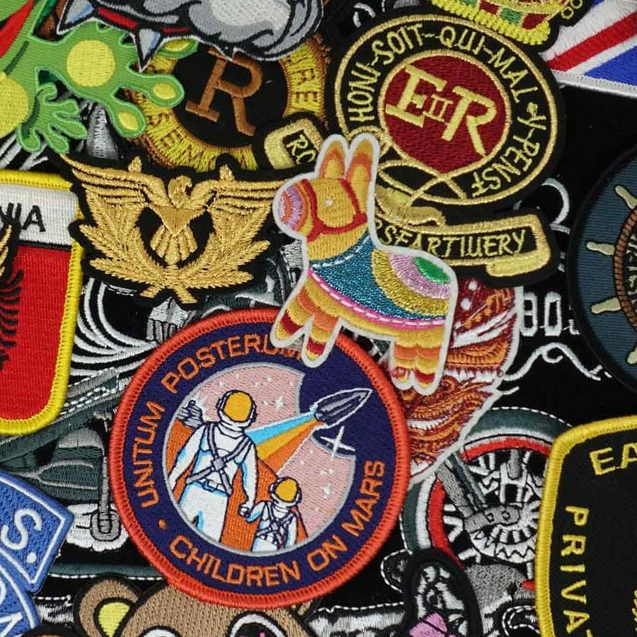 A colorful collection of embroidered patches, including symbols, emblems, and a childrens design with astronauts on Mars.
