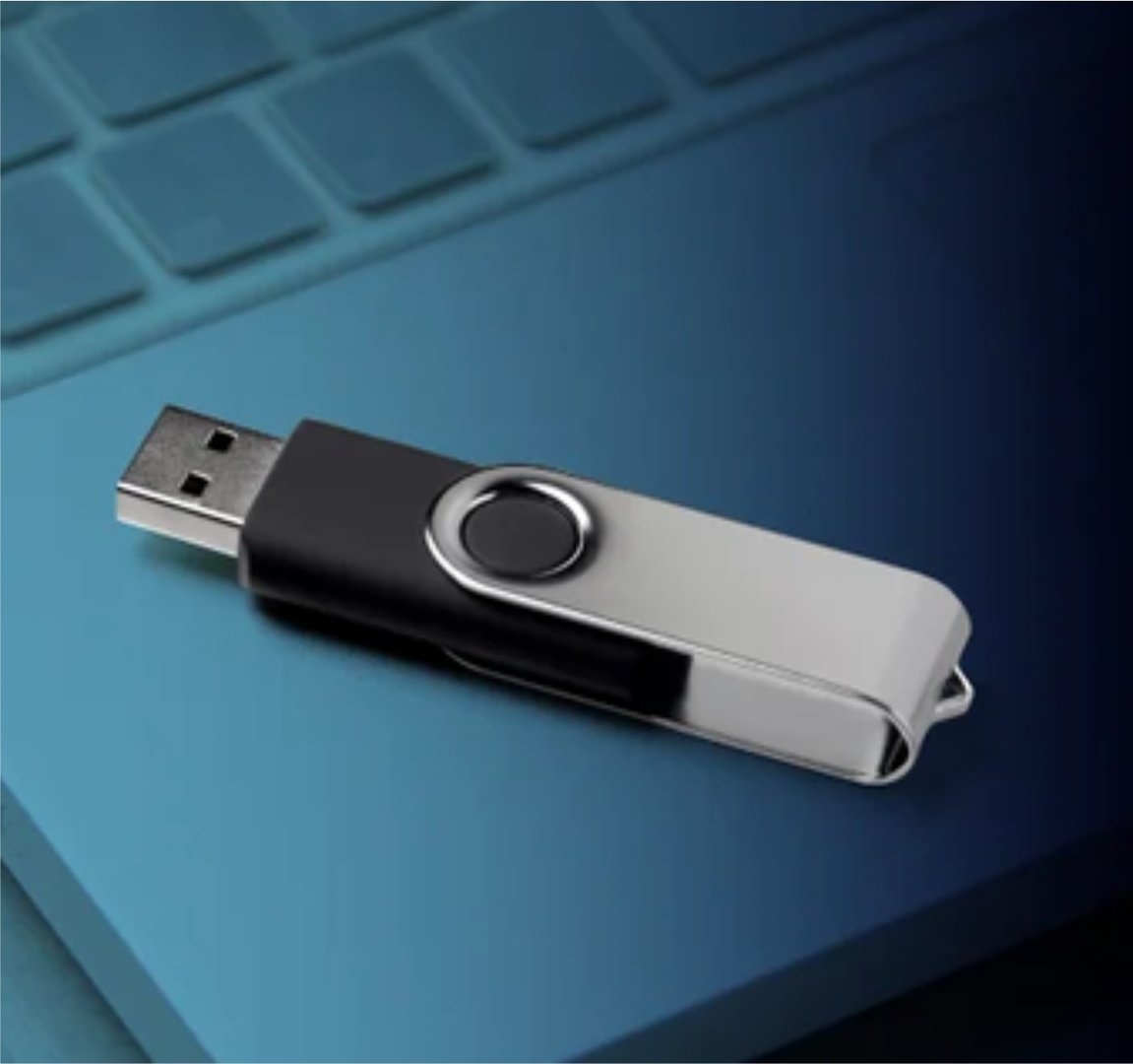USB flash drive with a swivel cover resting on a laptop keyboard.