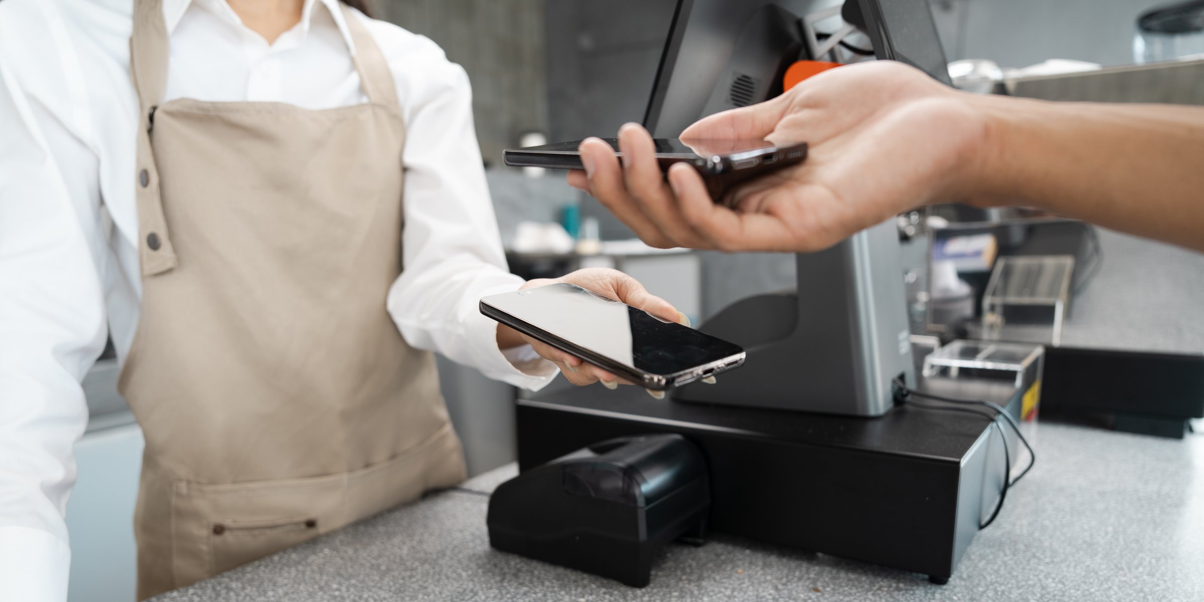 A customer making a contactless mobile payment at a retail store counter, showcasing modern technology and convenience in transactions.