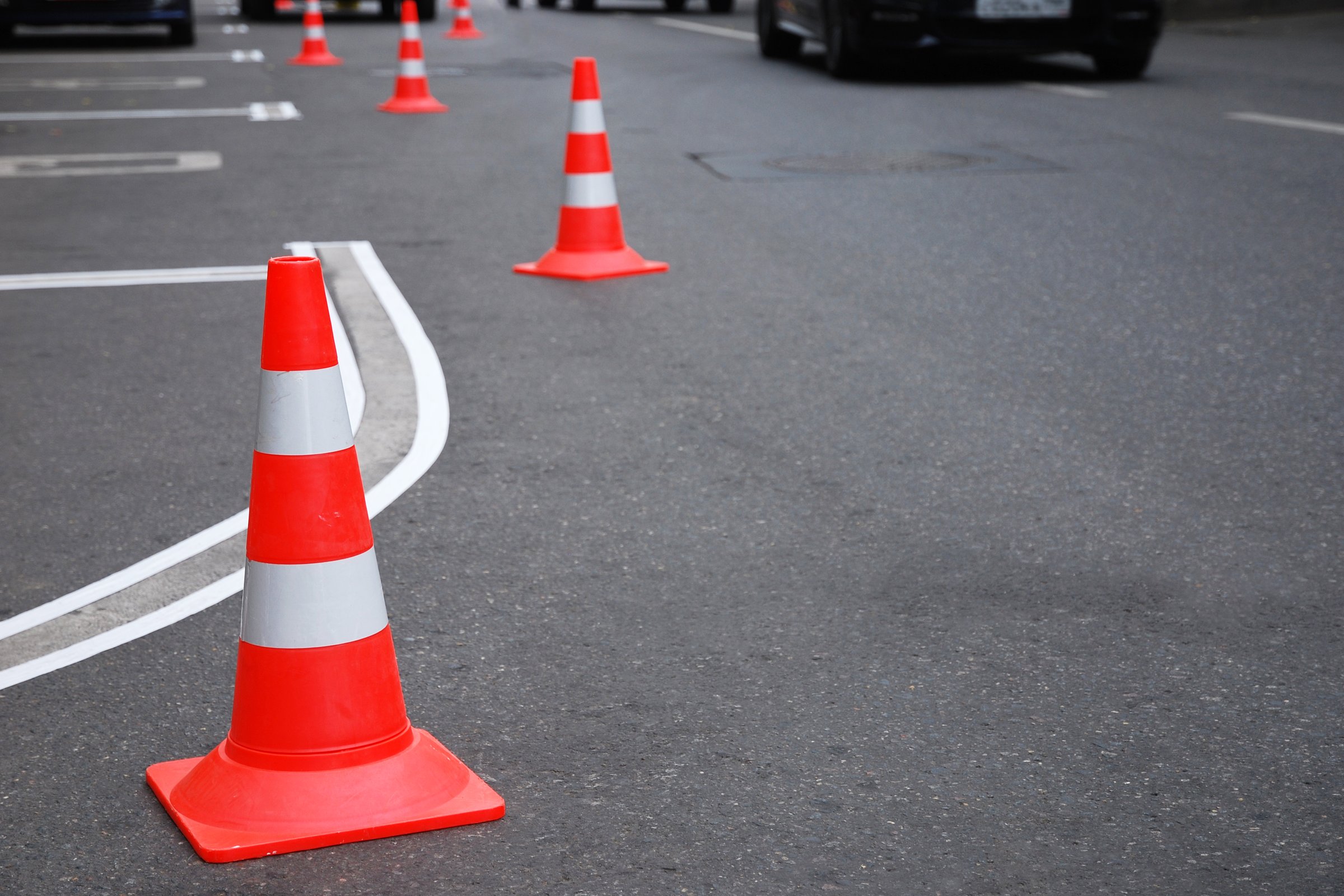 Renewing of parking marking on the road, special adhesive tape, traffic cones on asphalt