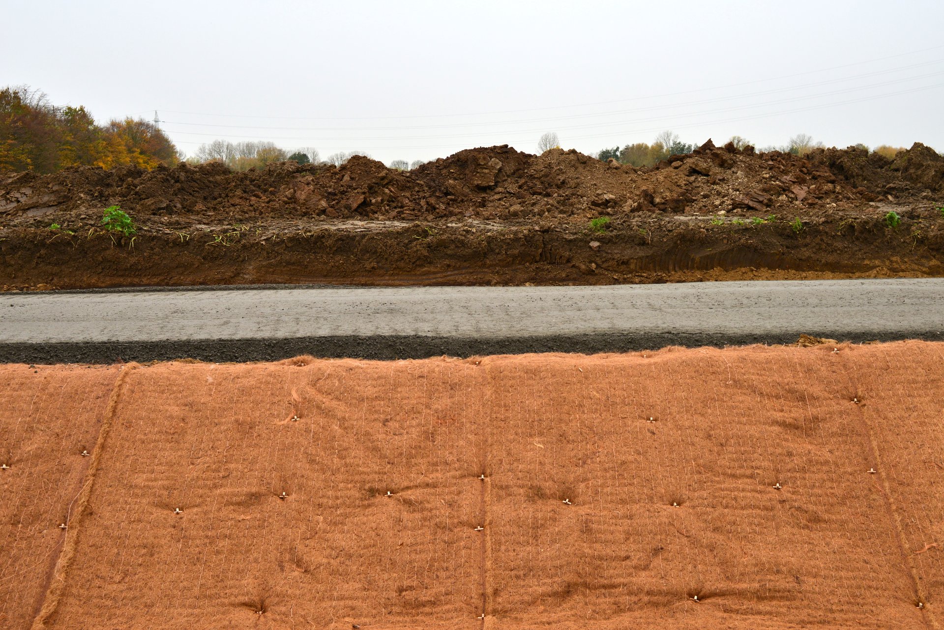 River banks are covered after the soil was excavated in slope shape and covered with a jute anti-weed water-permeable ground cover and held in place by hammering plastic pegs