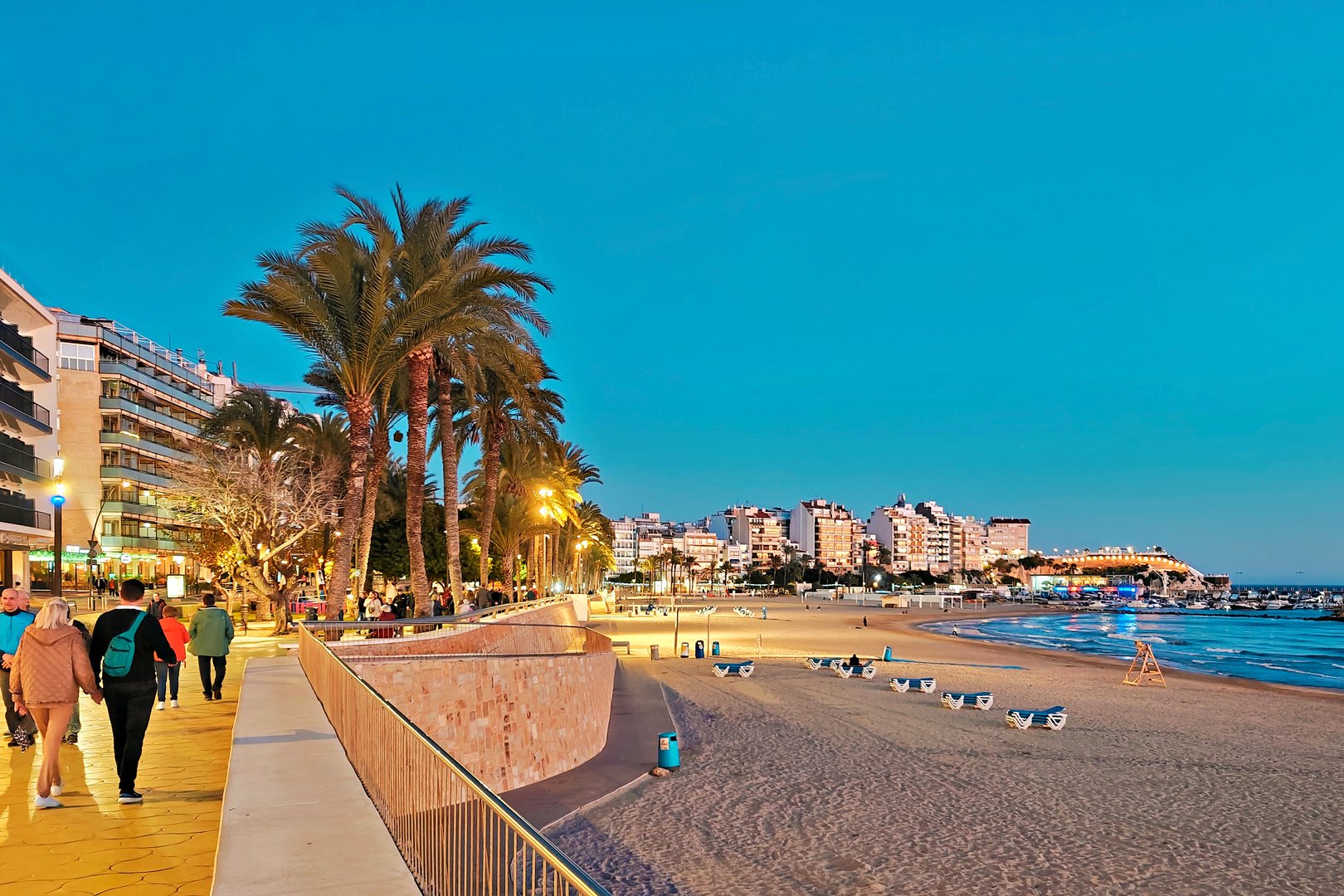 Benidorm, Spain - January 10, 2025: Seaside promenade near Poniente beach. People enjoy evening in popular spanish resort.