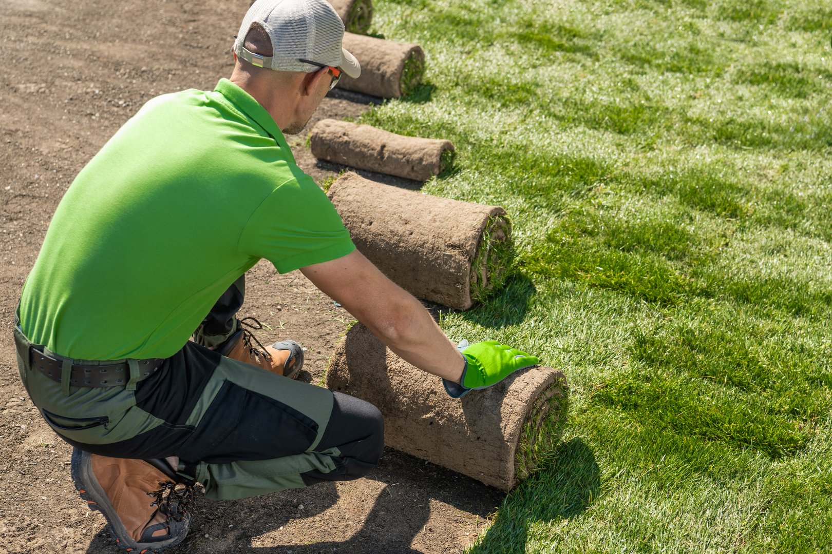 Gardener is carefully laying down grass on a lawn. Installing Grass Turfs.