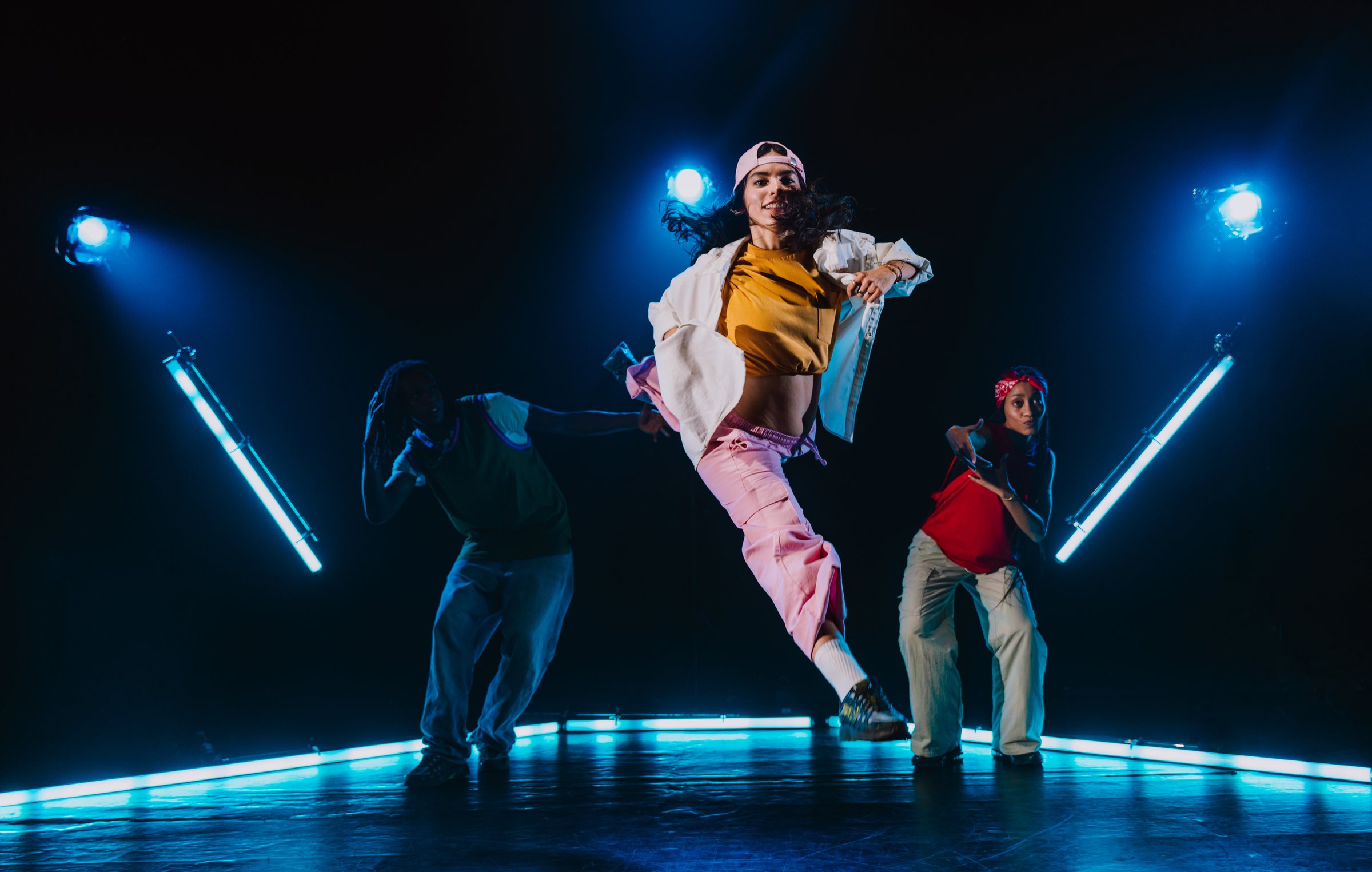 Group of hip hop dancer dancing together in a moody studio with tube neon lights.