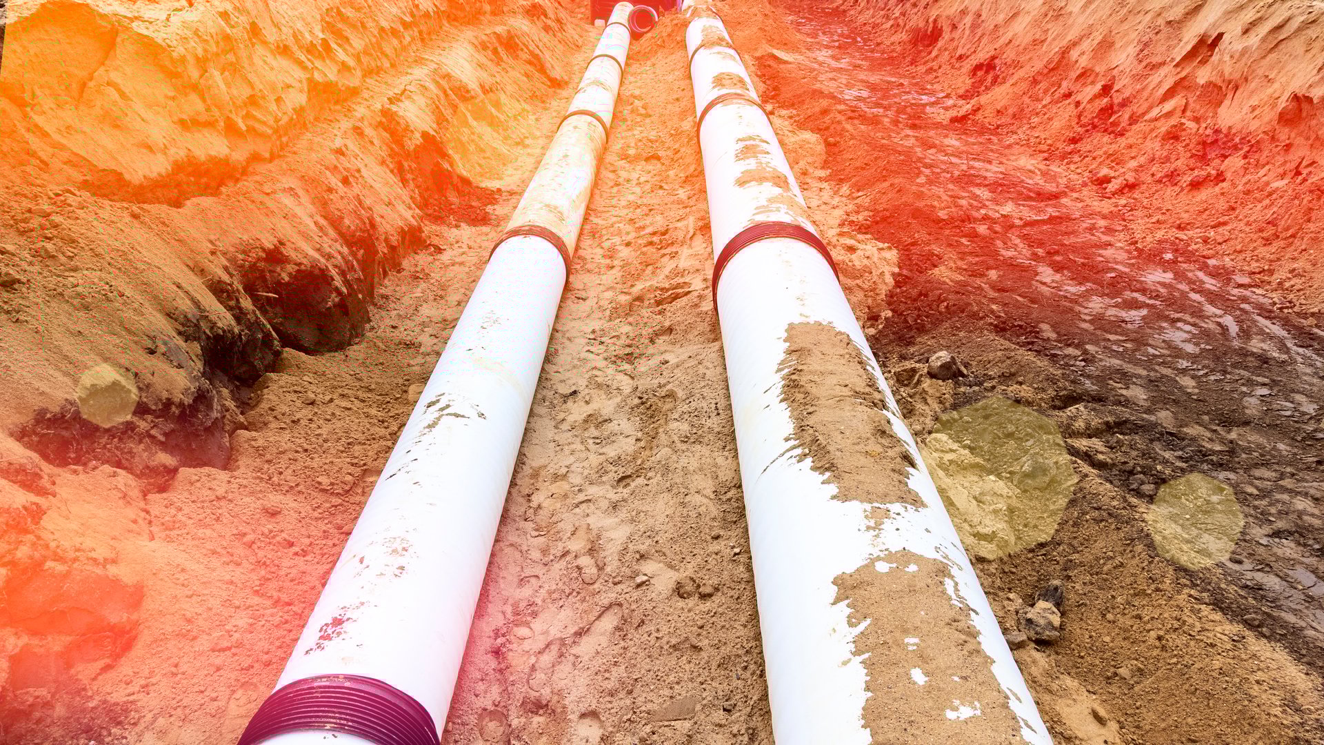 Plastic pipelines in the trench, construction work in civil construction of sewers and drainage networks top view of large white pipes in the trench, selective focusing of tinted image solar glare