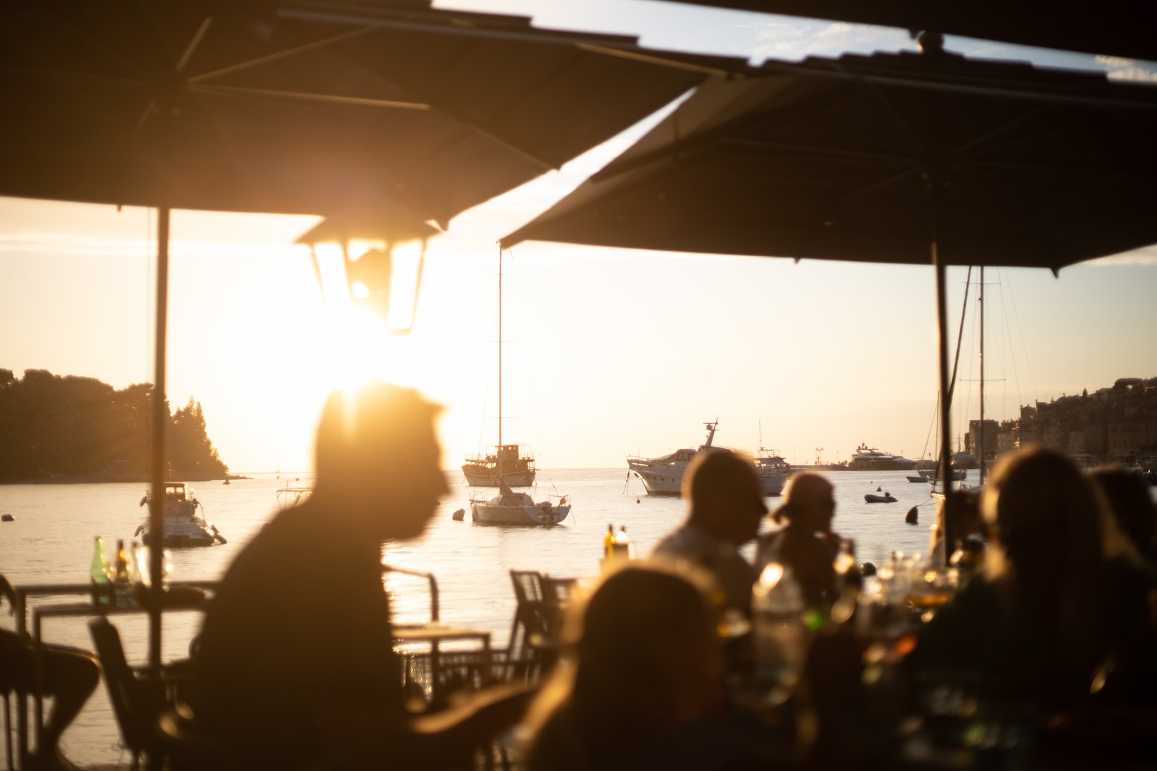 people dining at seaside restaurant with romantic sunset