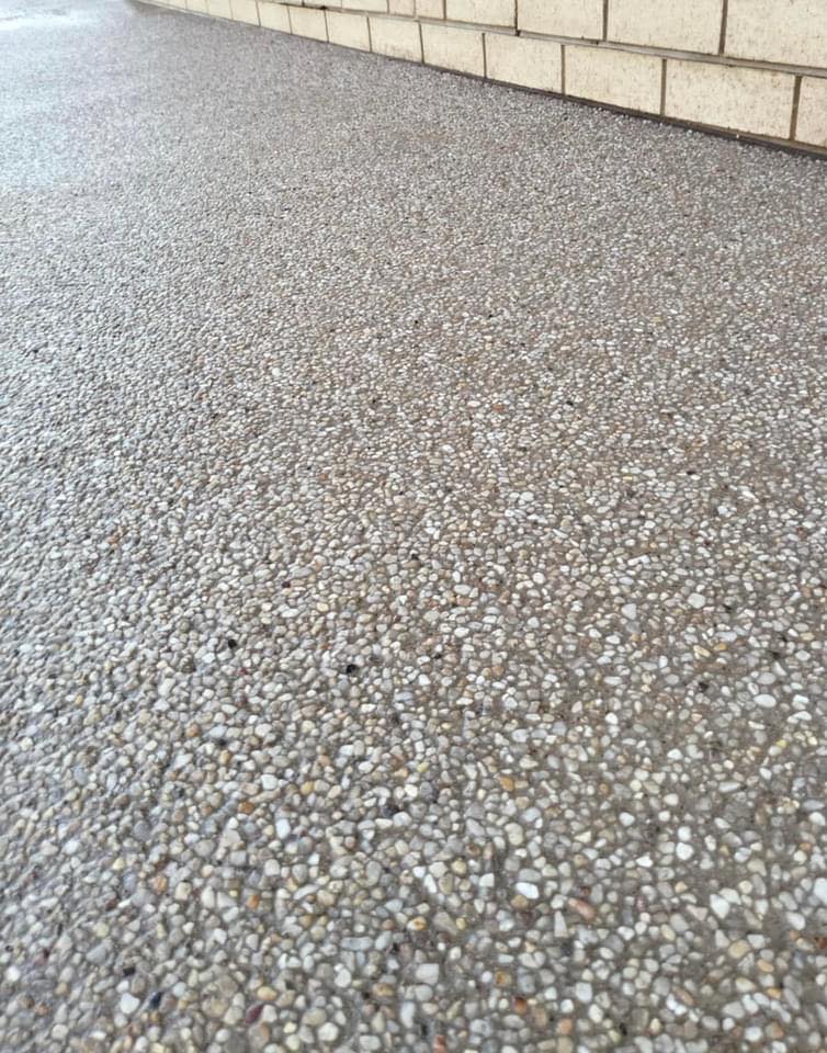 Close-up of a textured pebble concrete surface next to a brick wall.
