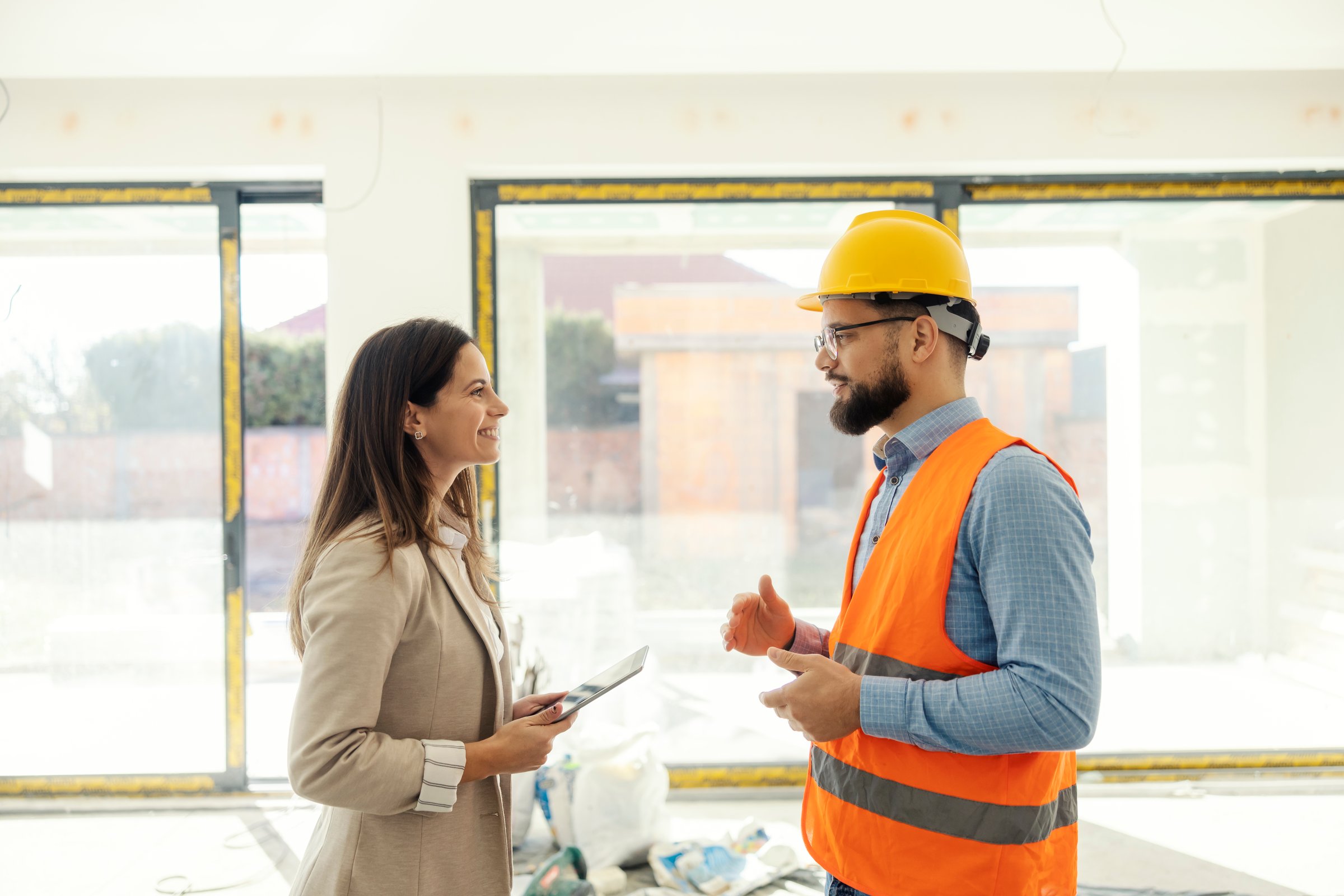 Side view of colleagues engineers with tablet discussing in building in building process.