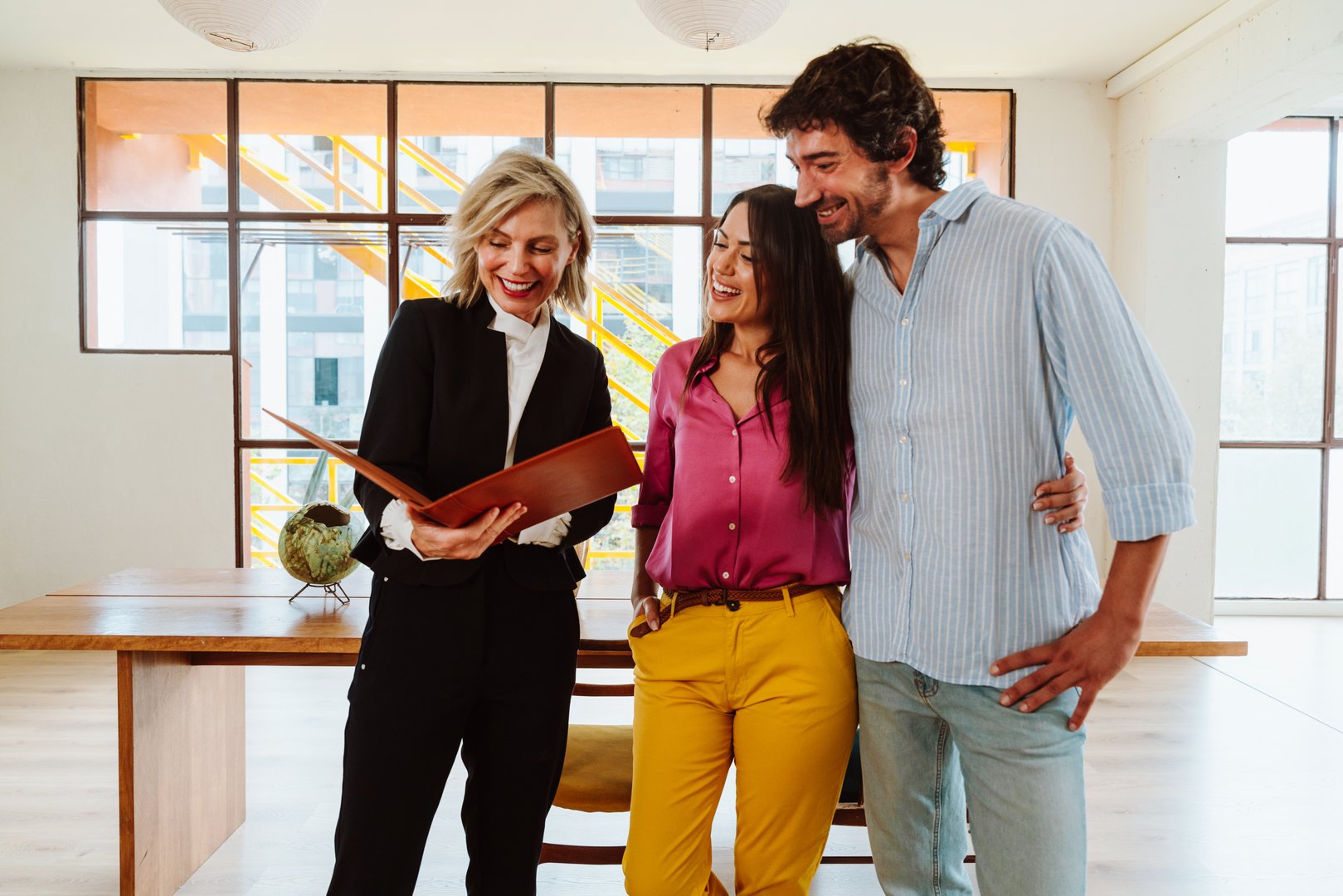 Real estate agent showing a new apartment and features of a good investment to a young couple. Woman and man buying a property in a rich area of the city.