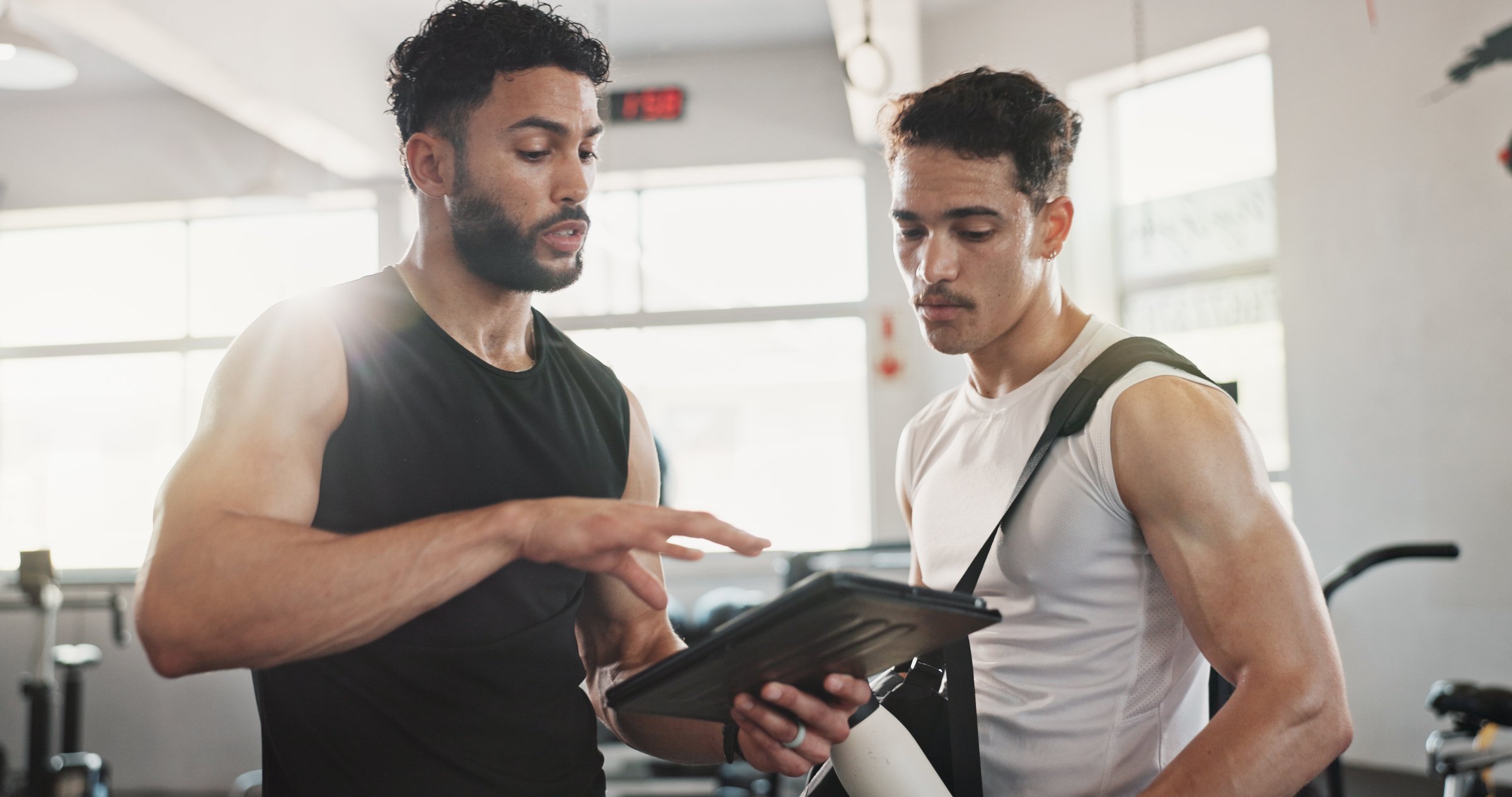 Fitness, advice and men in gym with tablet for online registration, planning or workout schedule. Athlete, personal trainer and digital app for exercise, progress results or membership at sports club