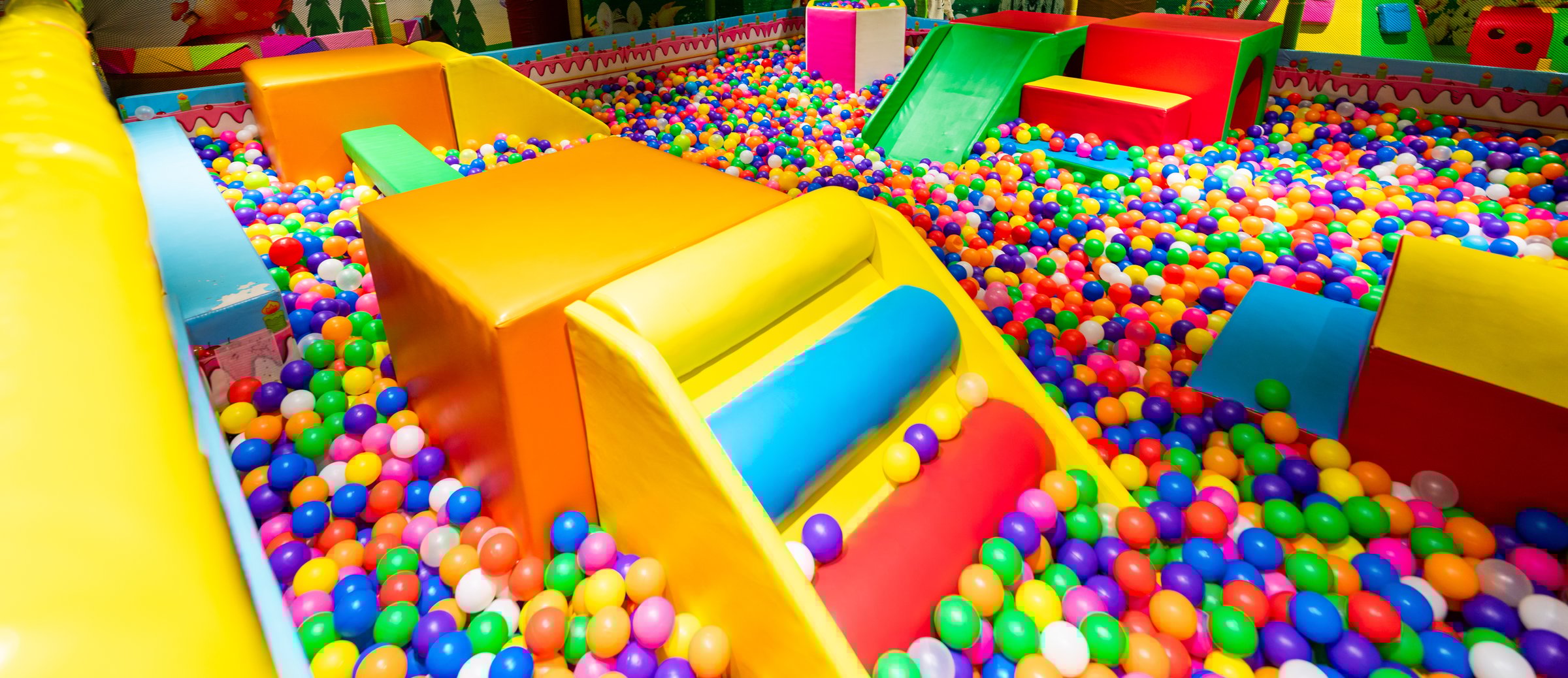 A colorful ball pit with soft play structures in a vibrant indoor playground