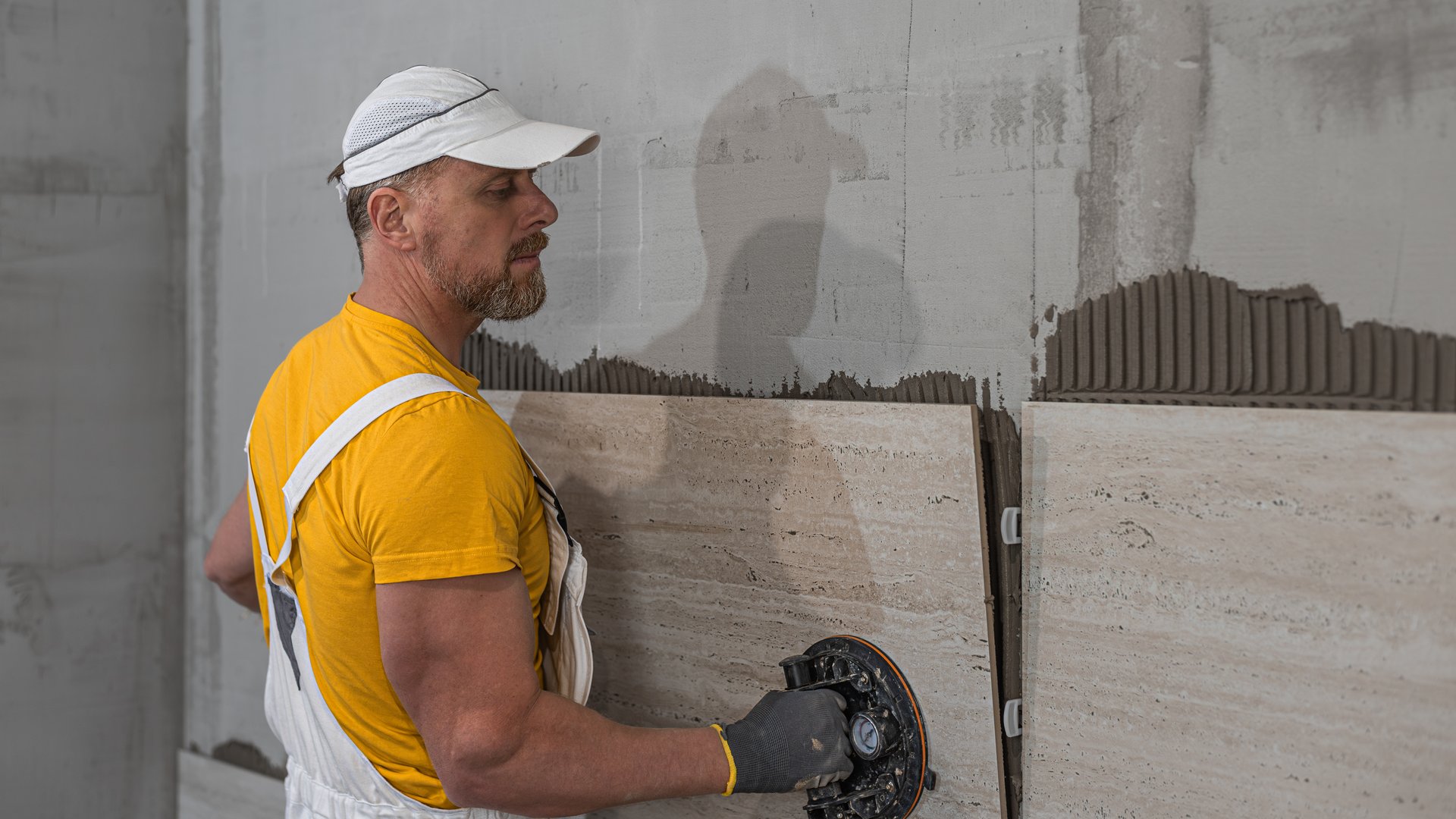 Tiling with large format tiles. A tiler placing a tile held by a tile suction cups.