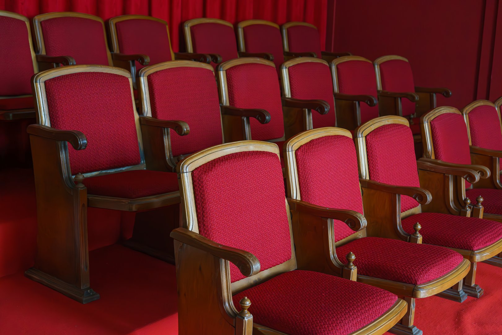 Empty rows of retro, old red theater or cinema seats. Old style, vintage chairs with red upholstery in concert hall.
