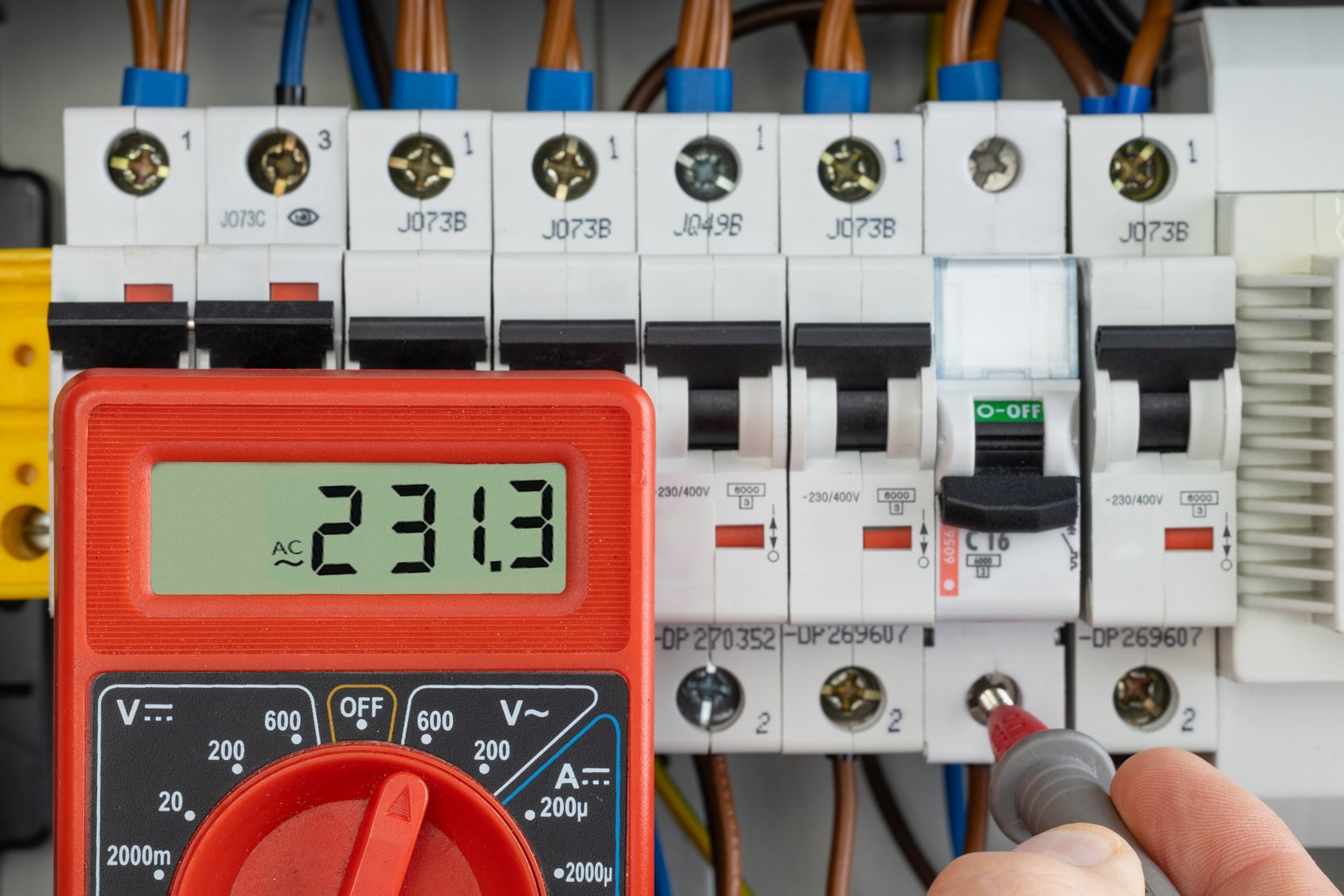 Multimeter used for testing voltage in a circuit breaker panel as part of electrical diagnostics.