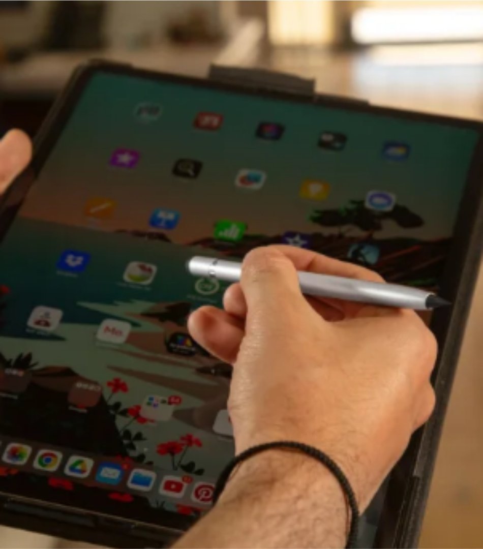 Person using a stylus on a tablet with colorful app icons displayed on the screen.