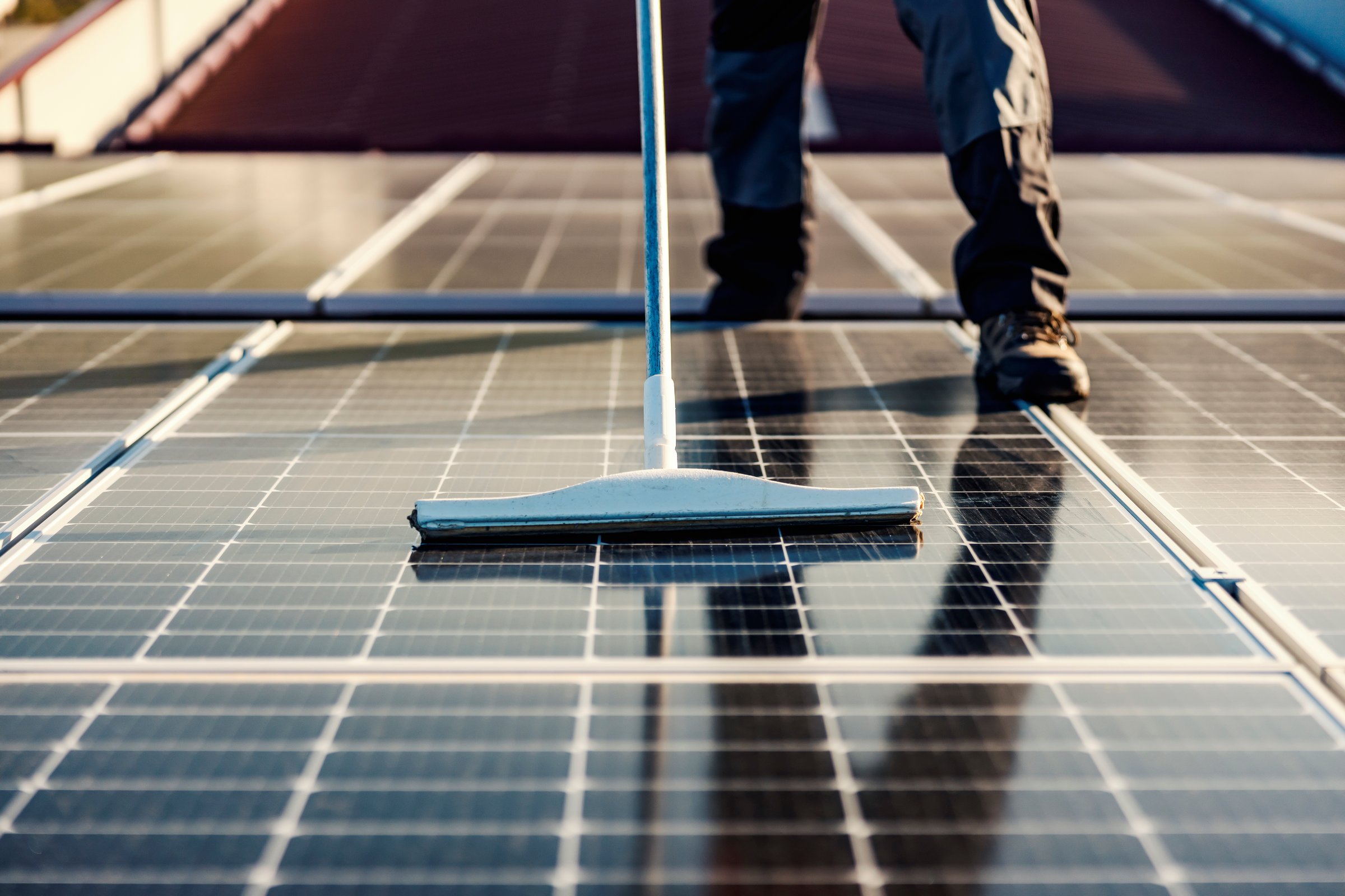 Close up of the broom cleaning solar panels on the rooftop.