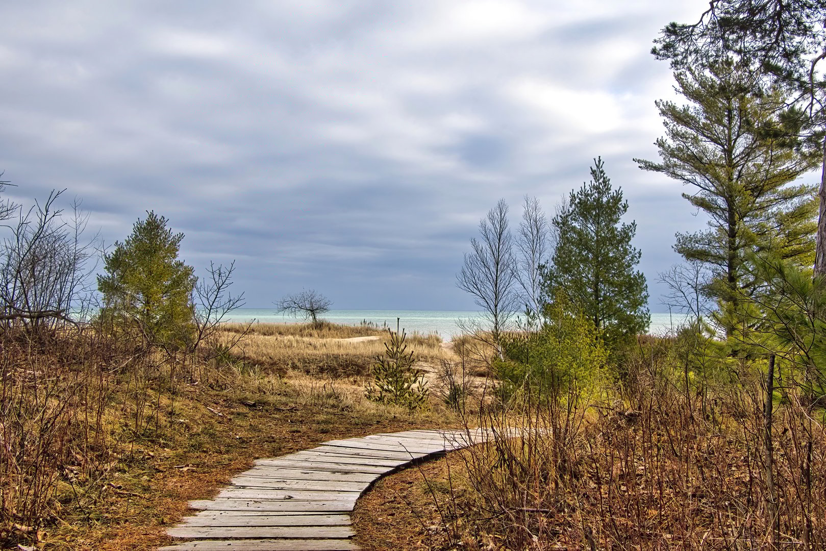 Cloudy Winter landscape of a wooden boardwalk curving through dunes along the Lake Michigan shoreline at Point Beach State Forest near Two Rivers, Wisconsin.