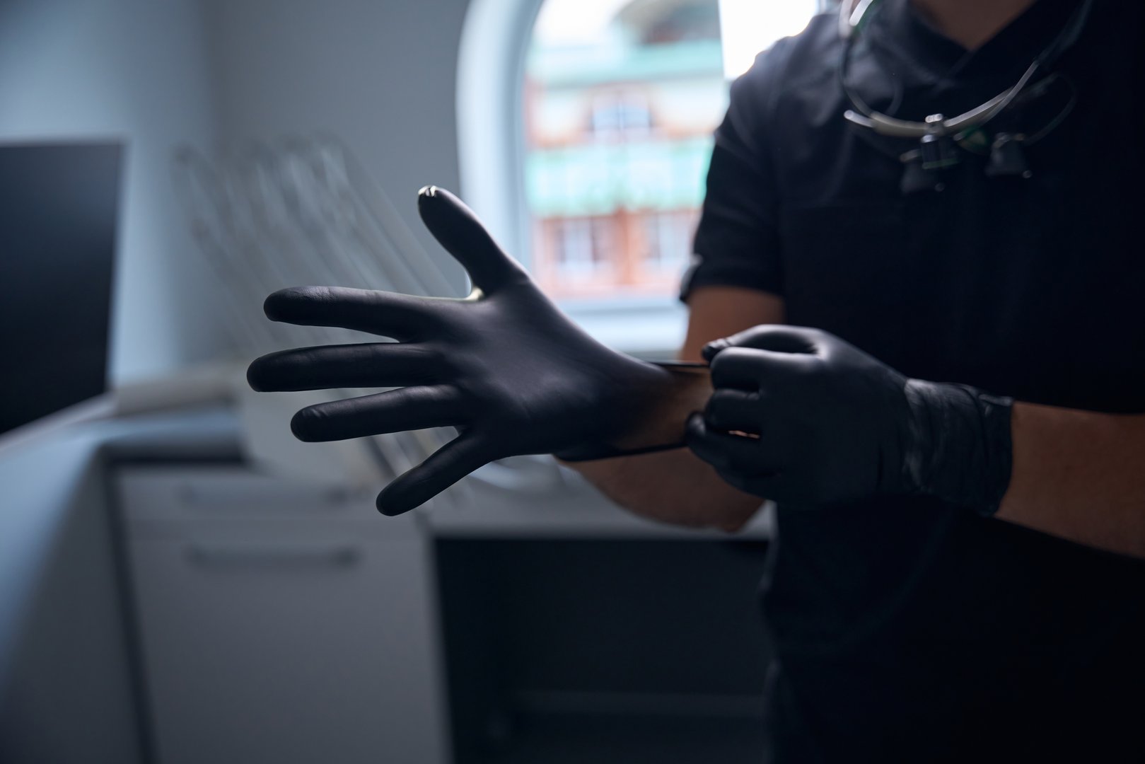 Medic puts on black protective gloves and wears a dark uniform