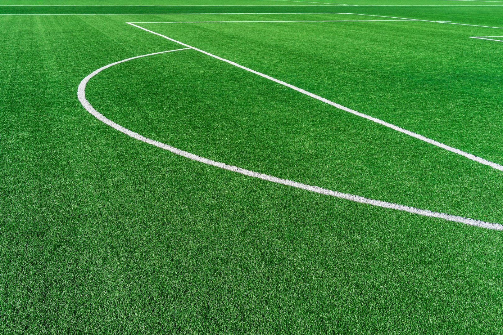 Soccer white marking lines of the Penalty arch area on artificial synthetic green grass turf