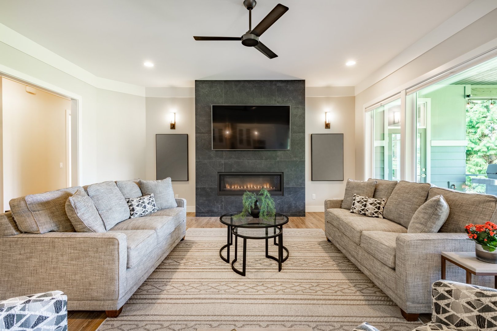 interior living room and kitchen in a modern contemporary custom built craftsman home rooms are open concept with classic and stylish decor fireplace with television set above area rug on the hardwood floor two sofas facing each other and large bright windows with view to golf course the kitchen has an expansive island stainless steel appliances light fixtures and the dining room has a dark wood table six chairs