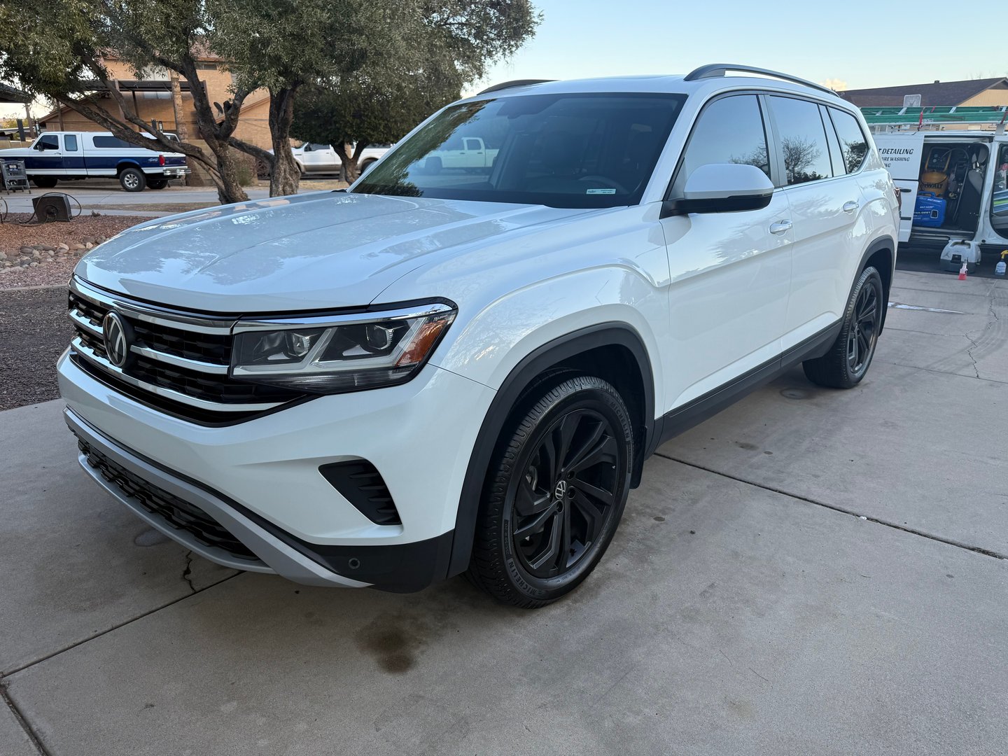 A white Volkswagen SUV parked on a driveway, featuring sleek black wheels and a modern front grille.