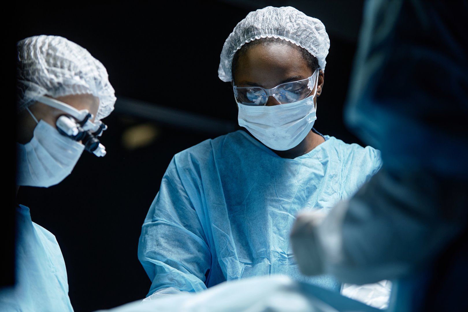 Waist up portrait of young African American woman as female surgeon with medical team in operating room